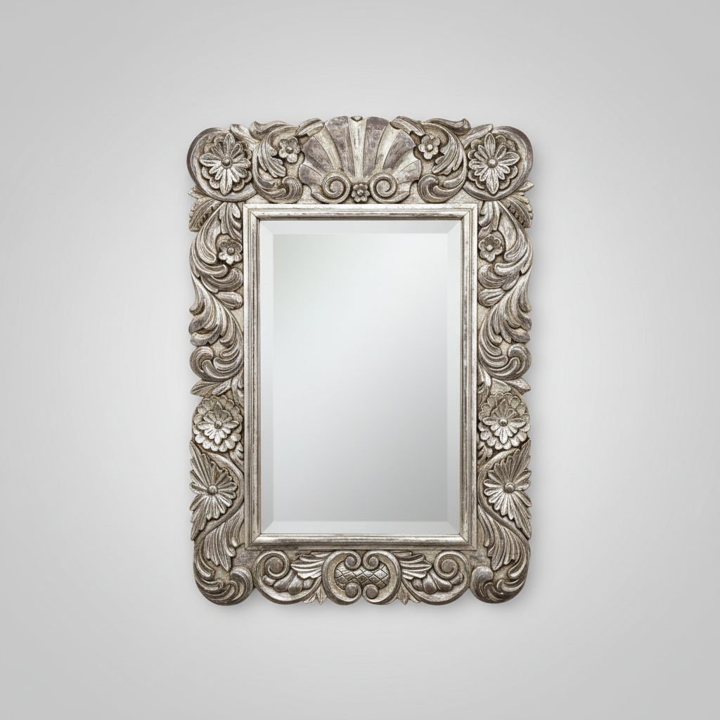 Decorative silver mirror with intricate patterns on a white wall