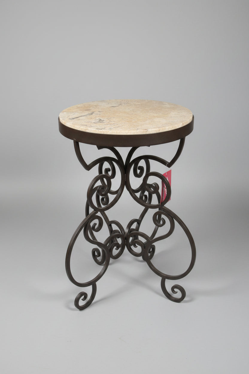 Round marble table with decorative metal base on a concrete floor.