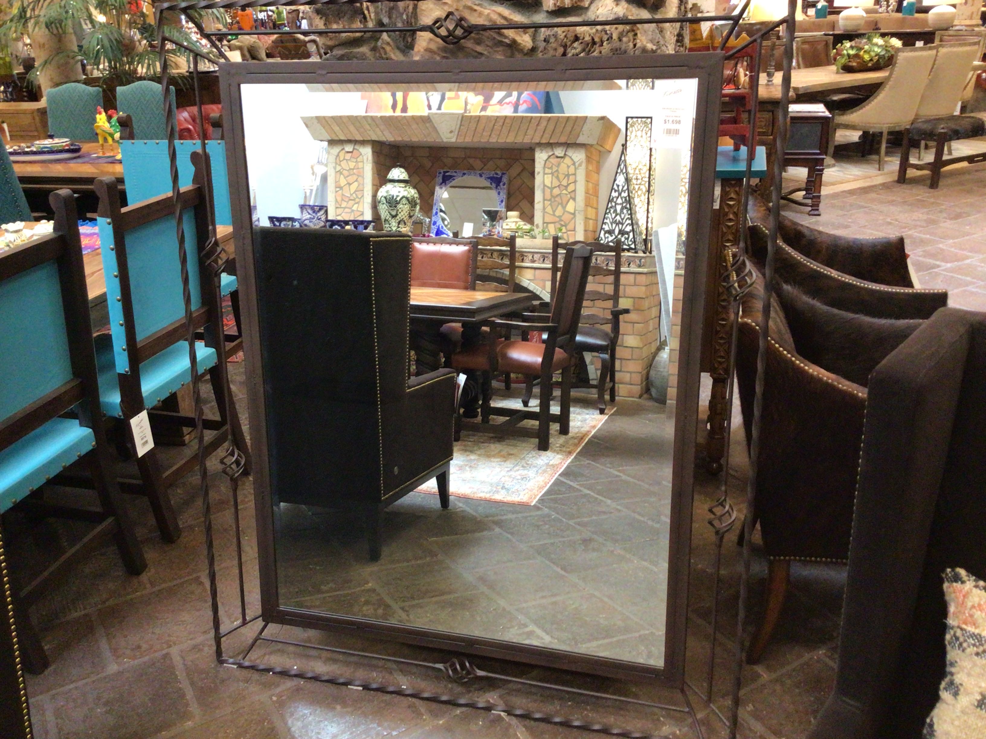 Large decorative mirror with a reflective surface showing a room interior.