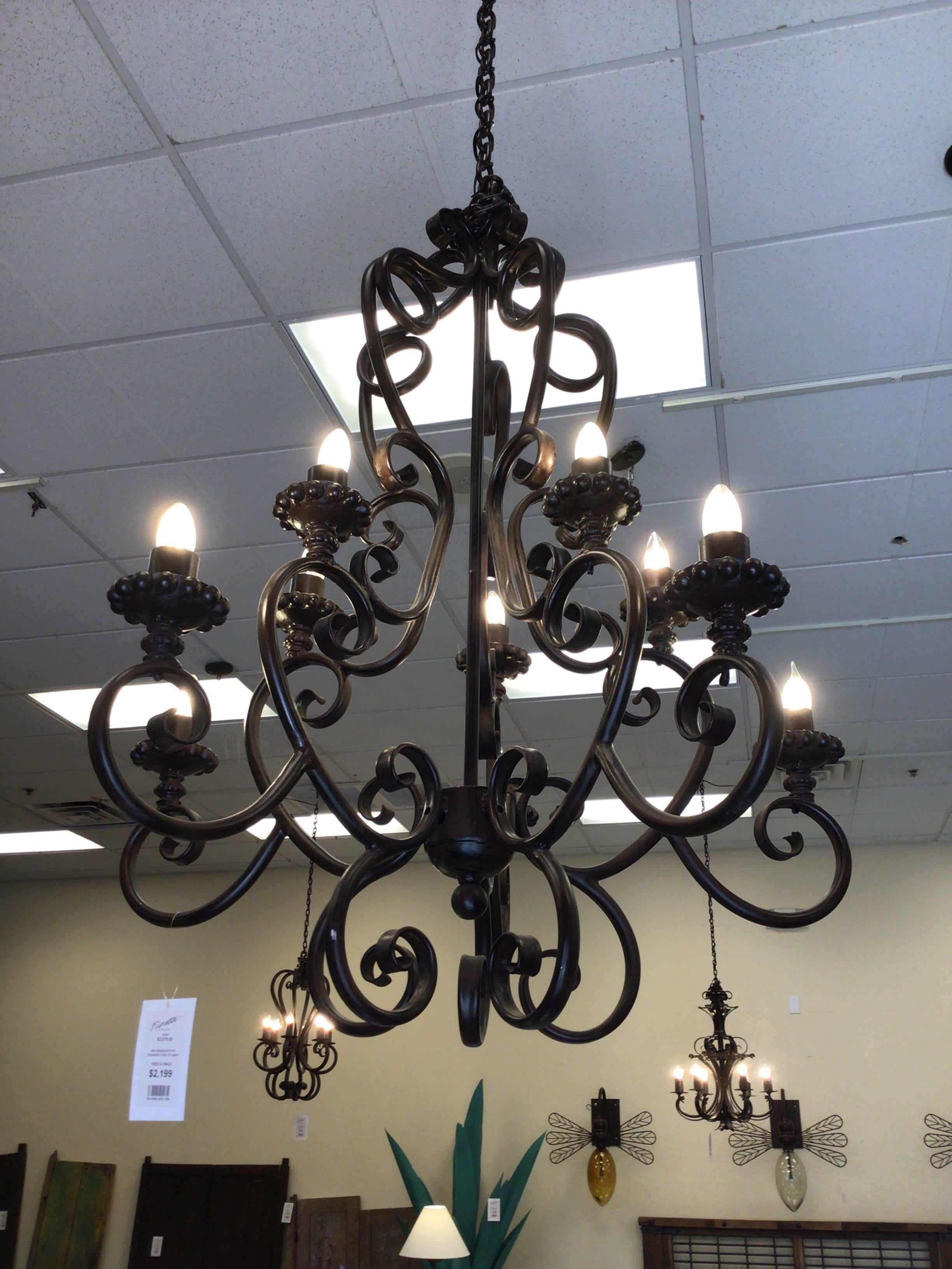 Wrought iron chandelier hanging from a ceiling in a store setting.