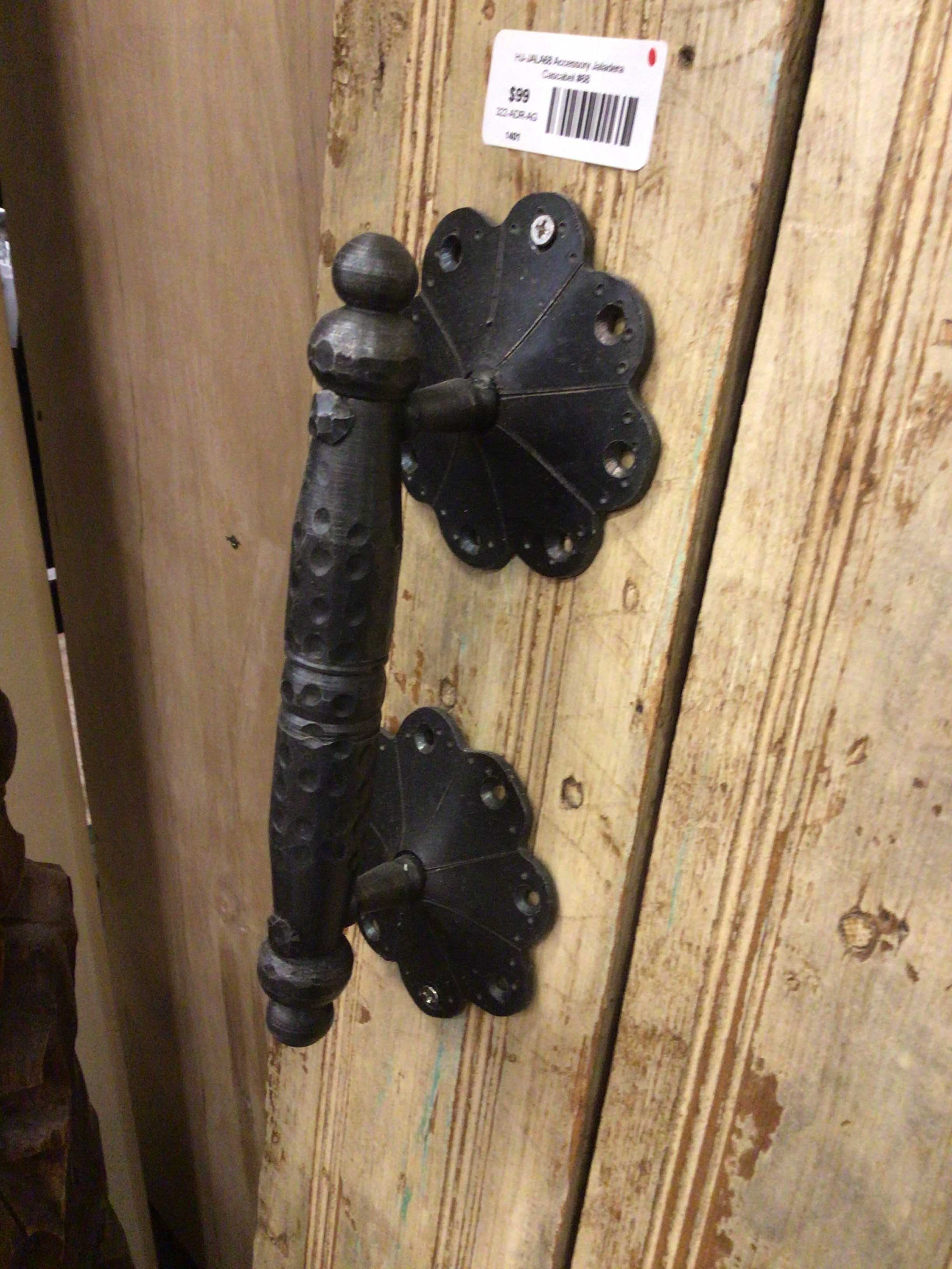 Decorative black metal handle on a wooden surface with a price tag.