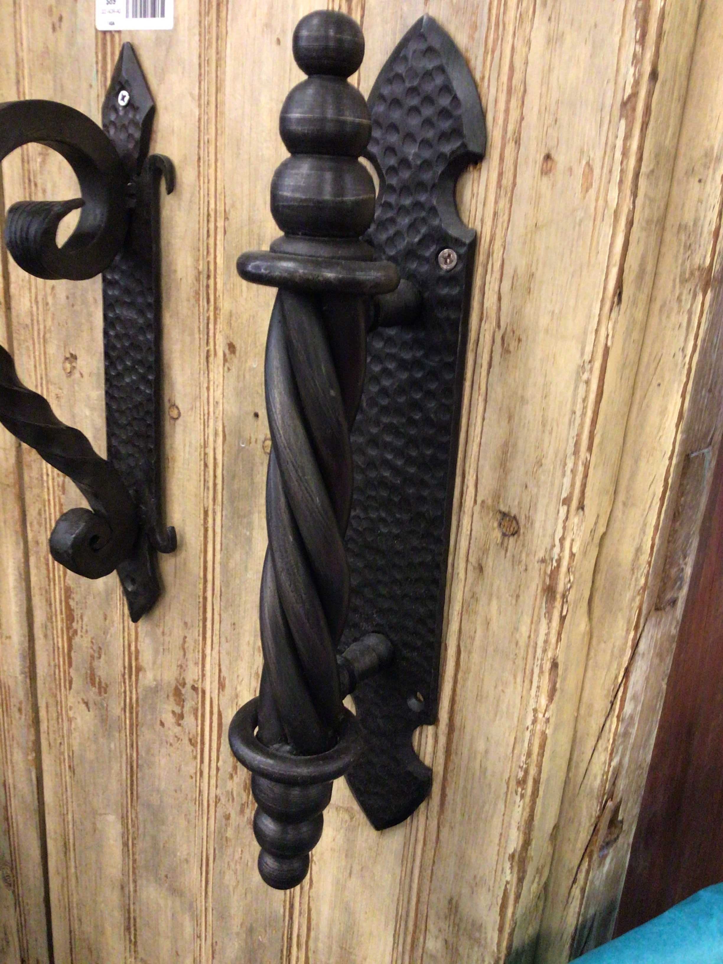 Decorative black metal door handle on a wooden background