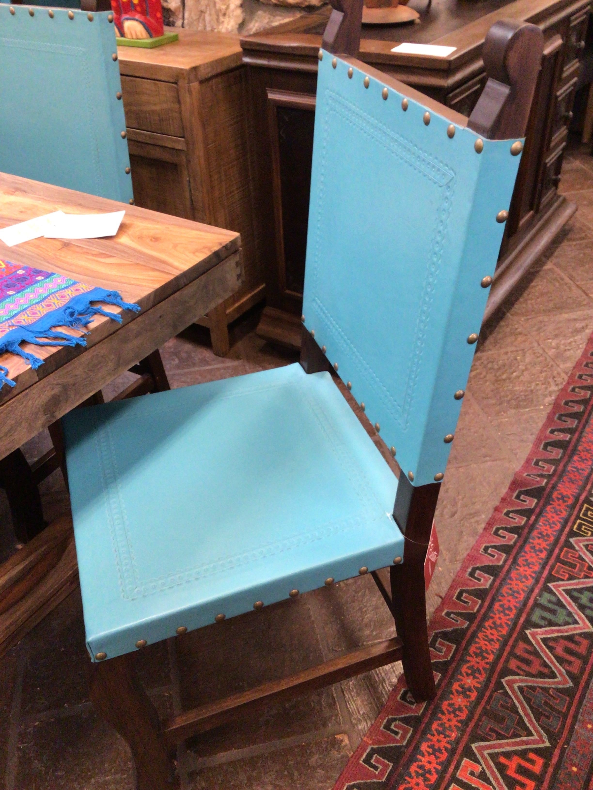 Blue chair with wooden frame in a room with wooden furniture and a patterned rug.