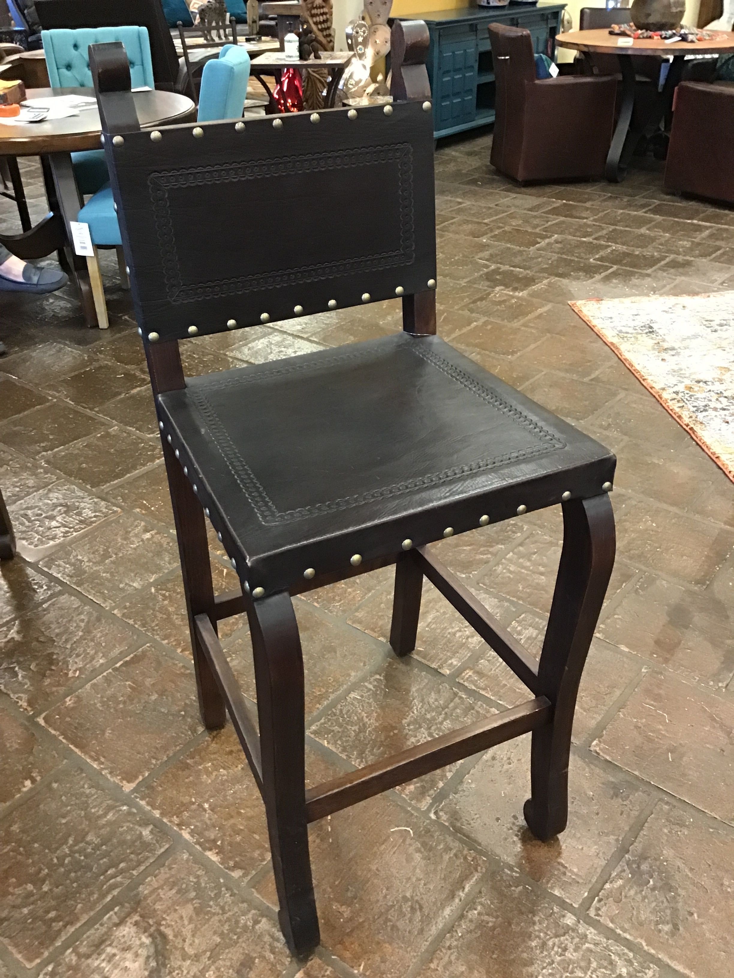 brown leather chair with studded details on a stone floor