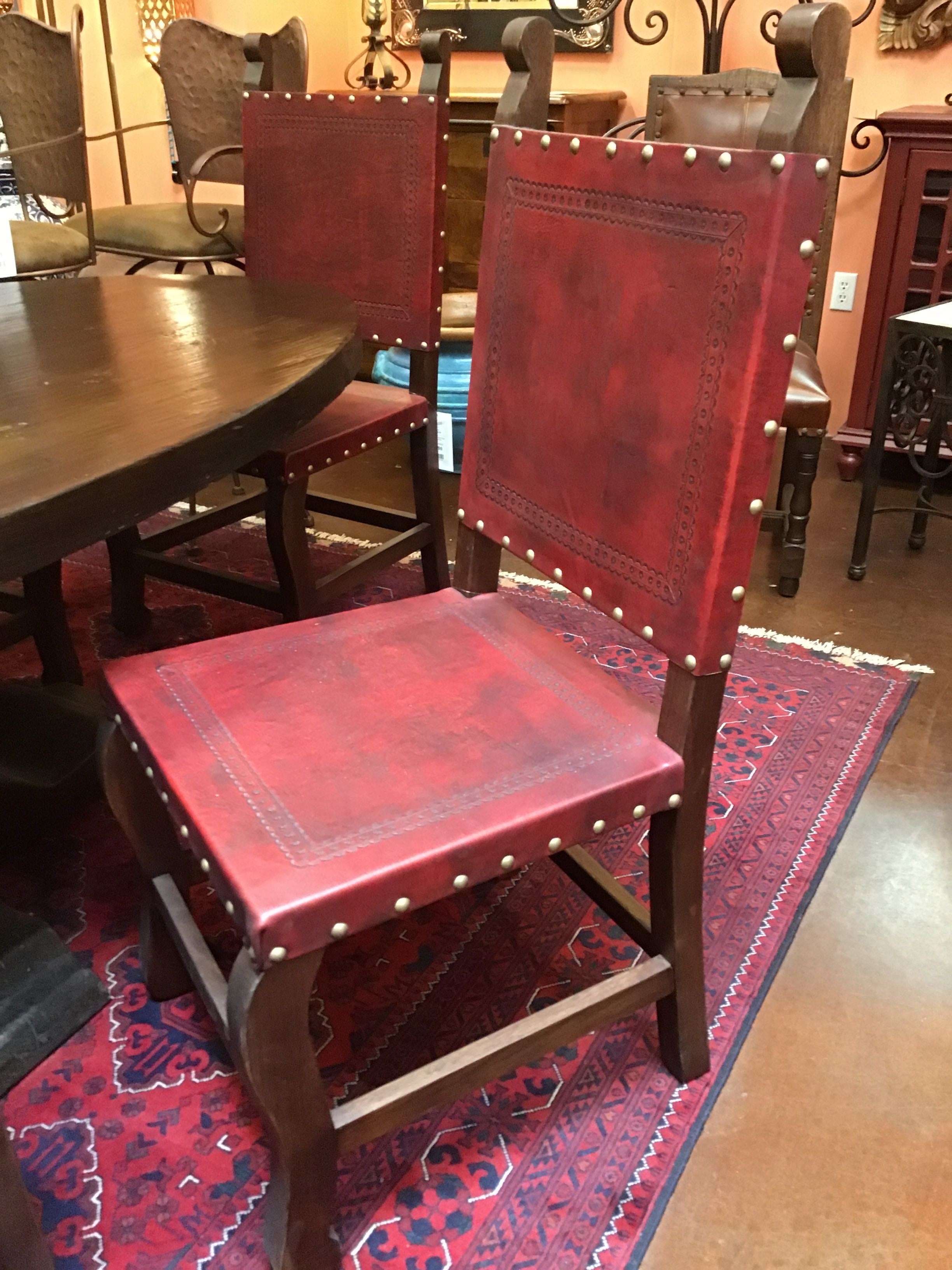 Red leather chair with studded details on a patterned rug in a room with furniture.