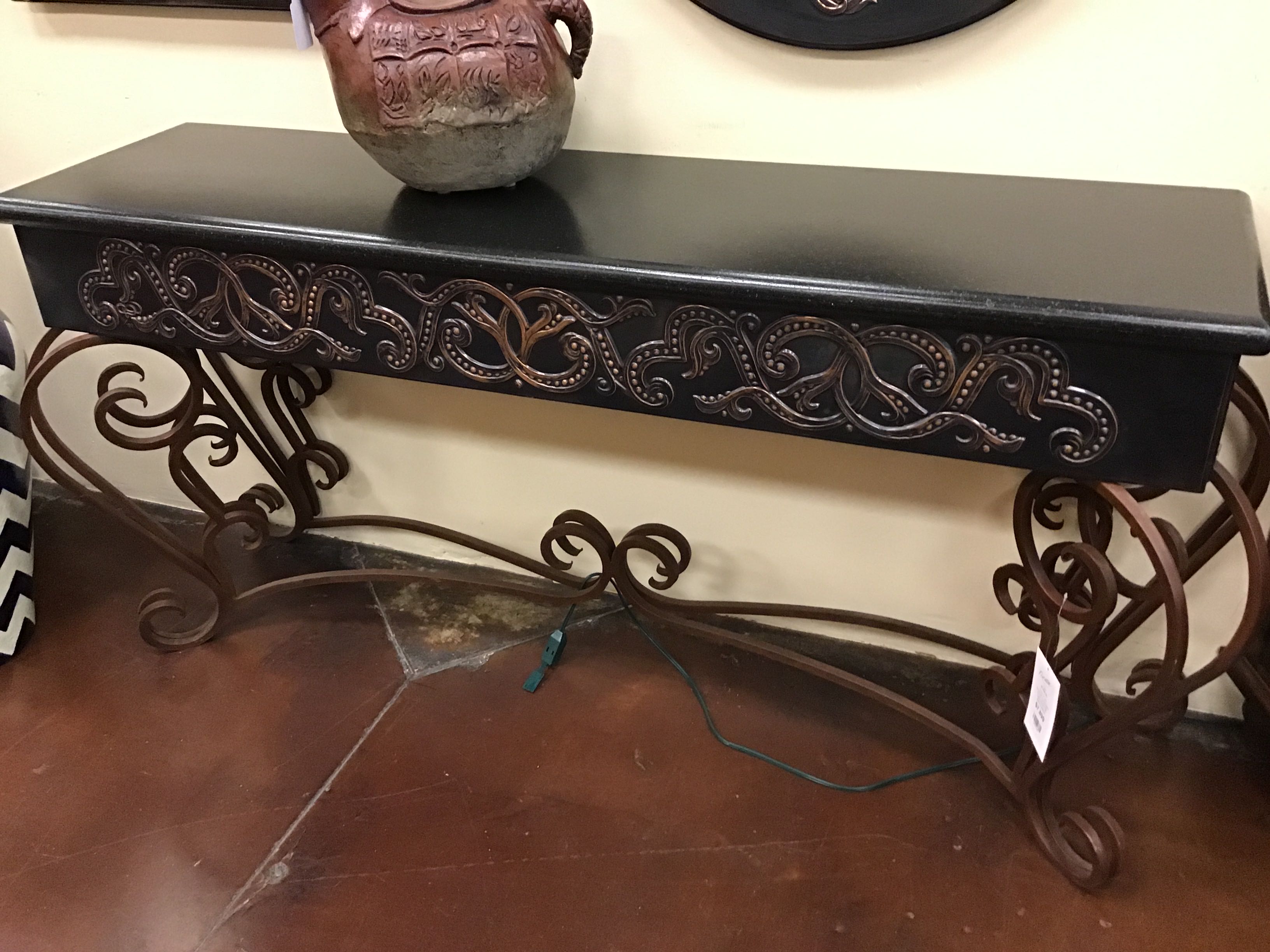 Decorative console table with intricate carvings on a wooden floor.