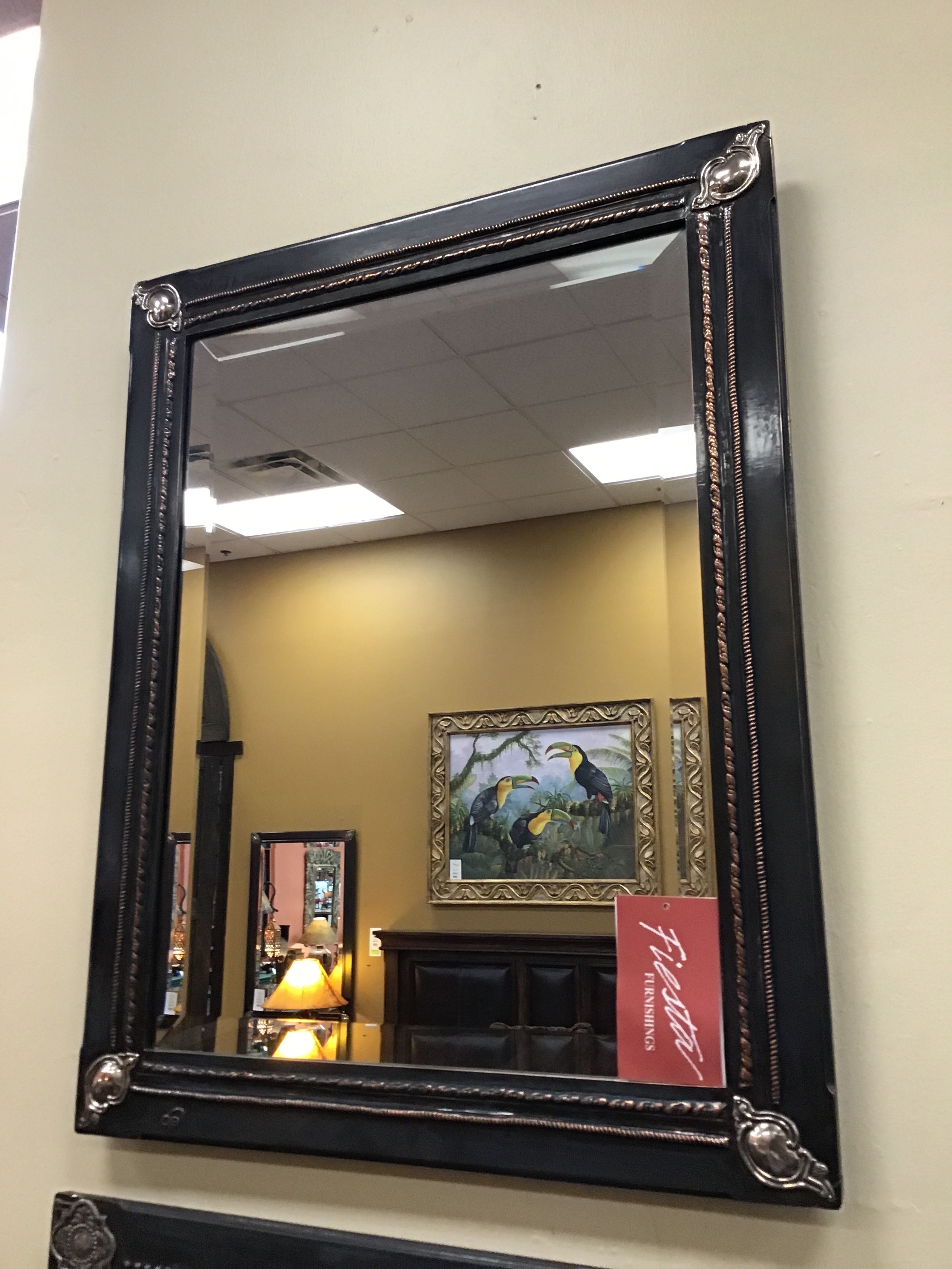 Black framed mirror with decorative trim on a wall