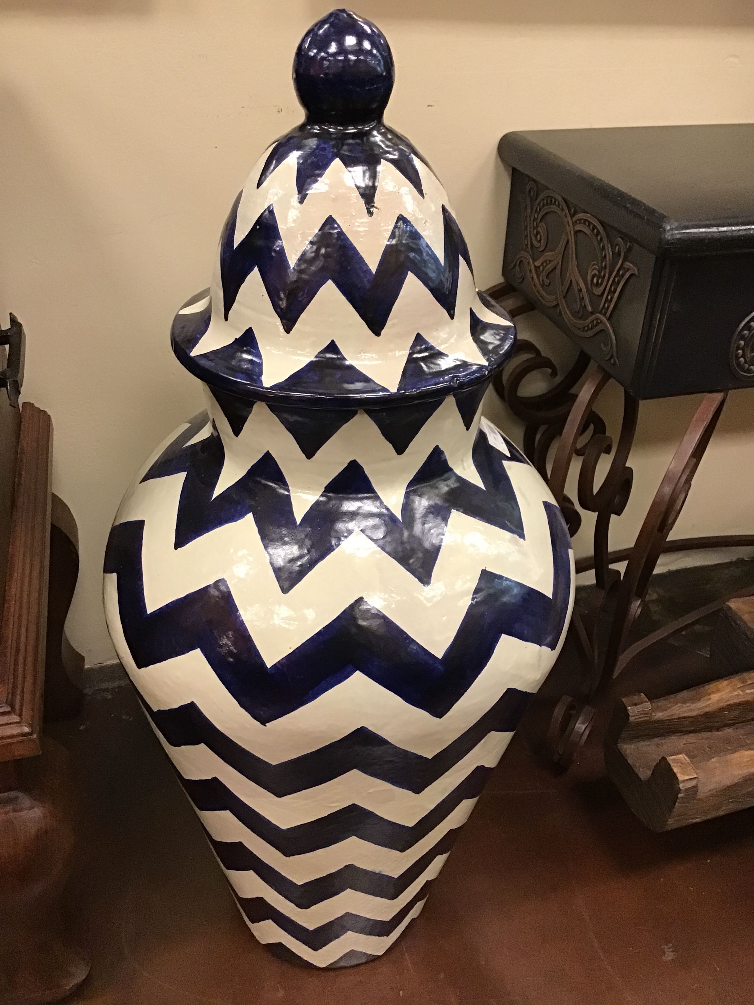 Decorative vase with blue and white zigzag pattern on a wooden floor.