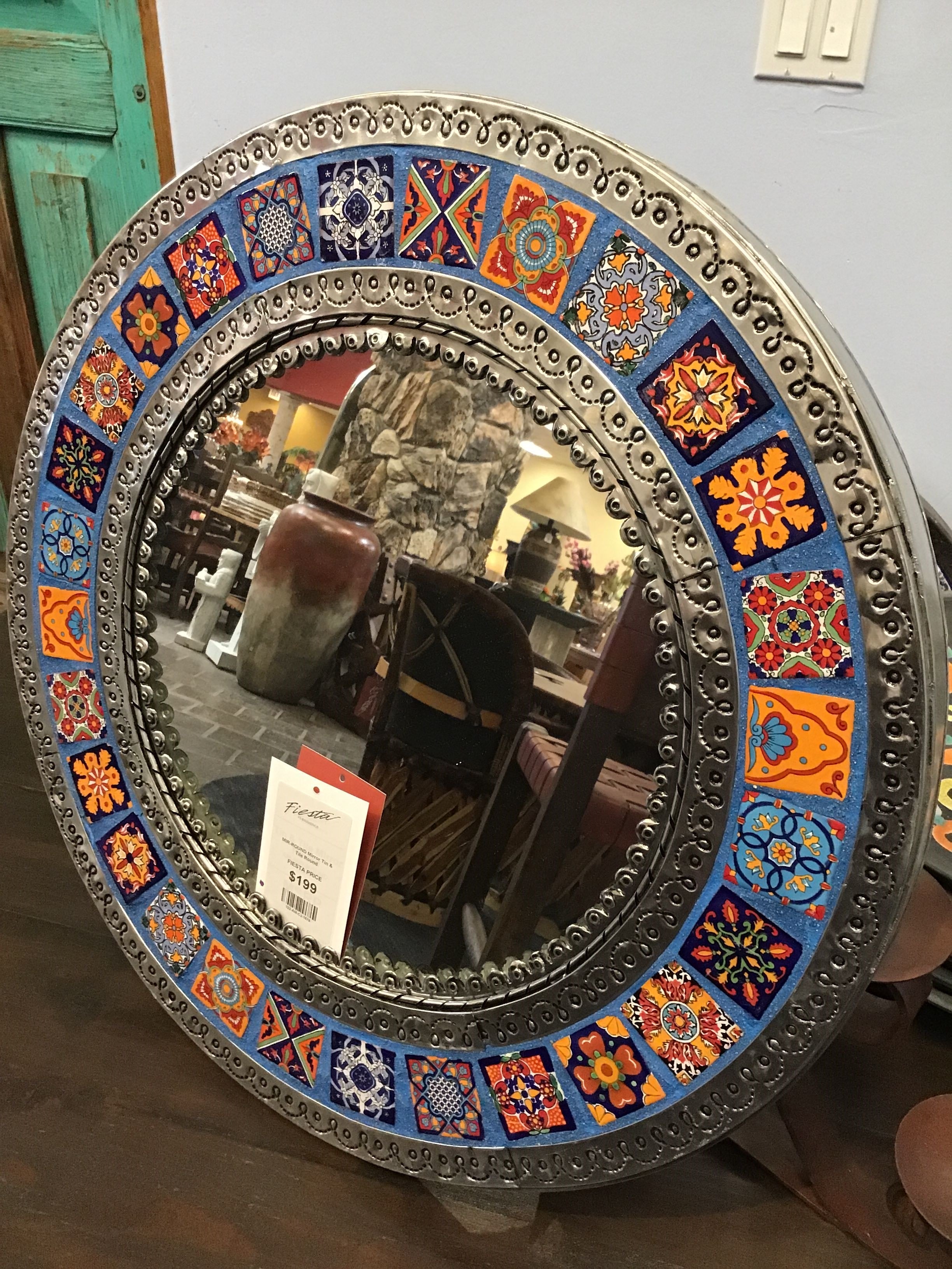 Decorative round mirror with colorful border on a wooden surface.