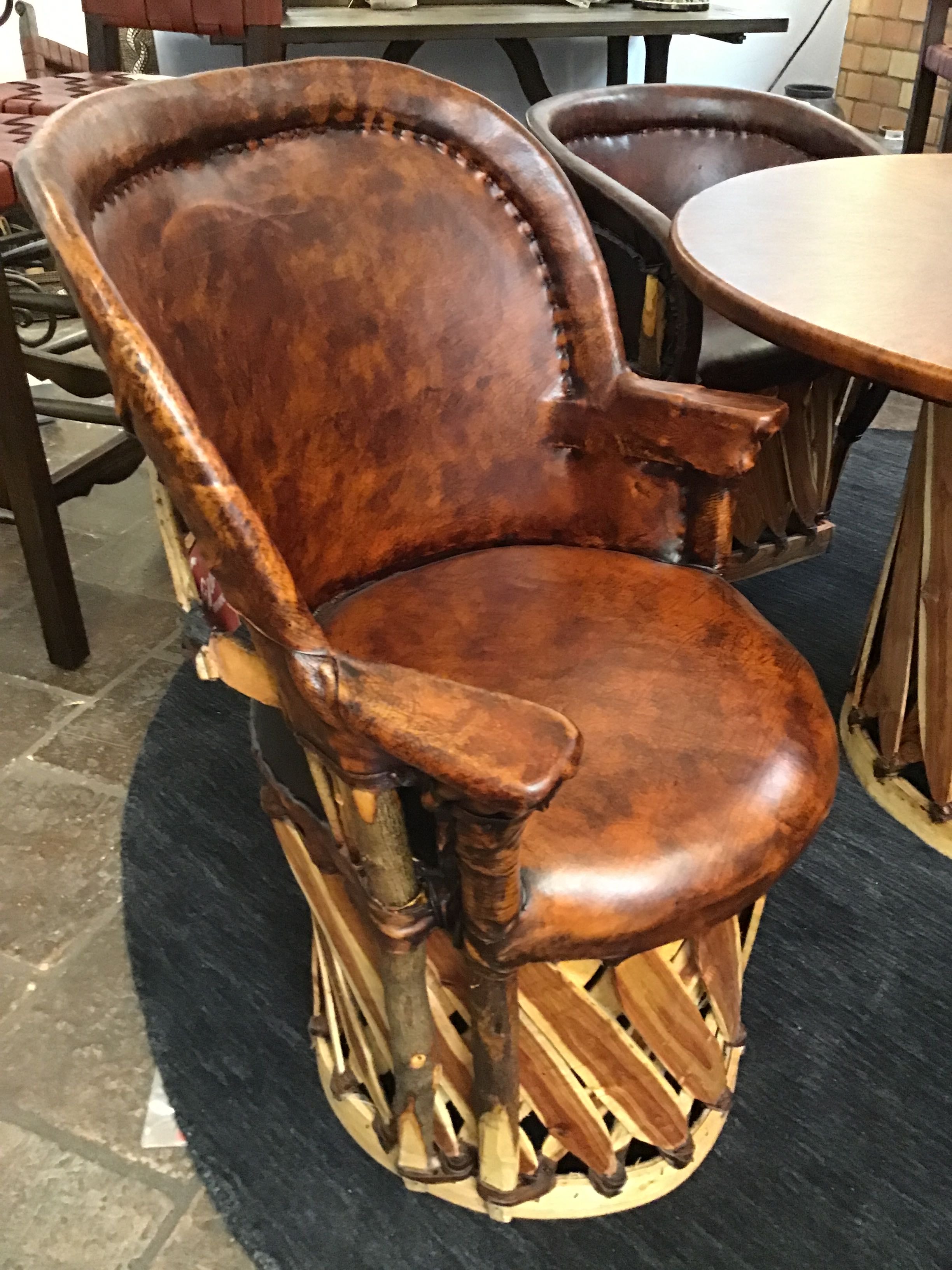 Brown leather chair with wooden base on a dark rug