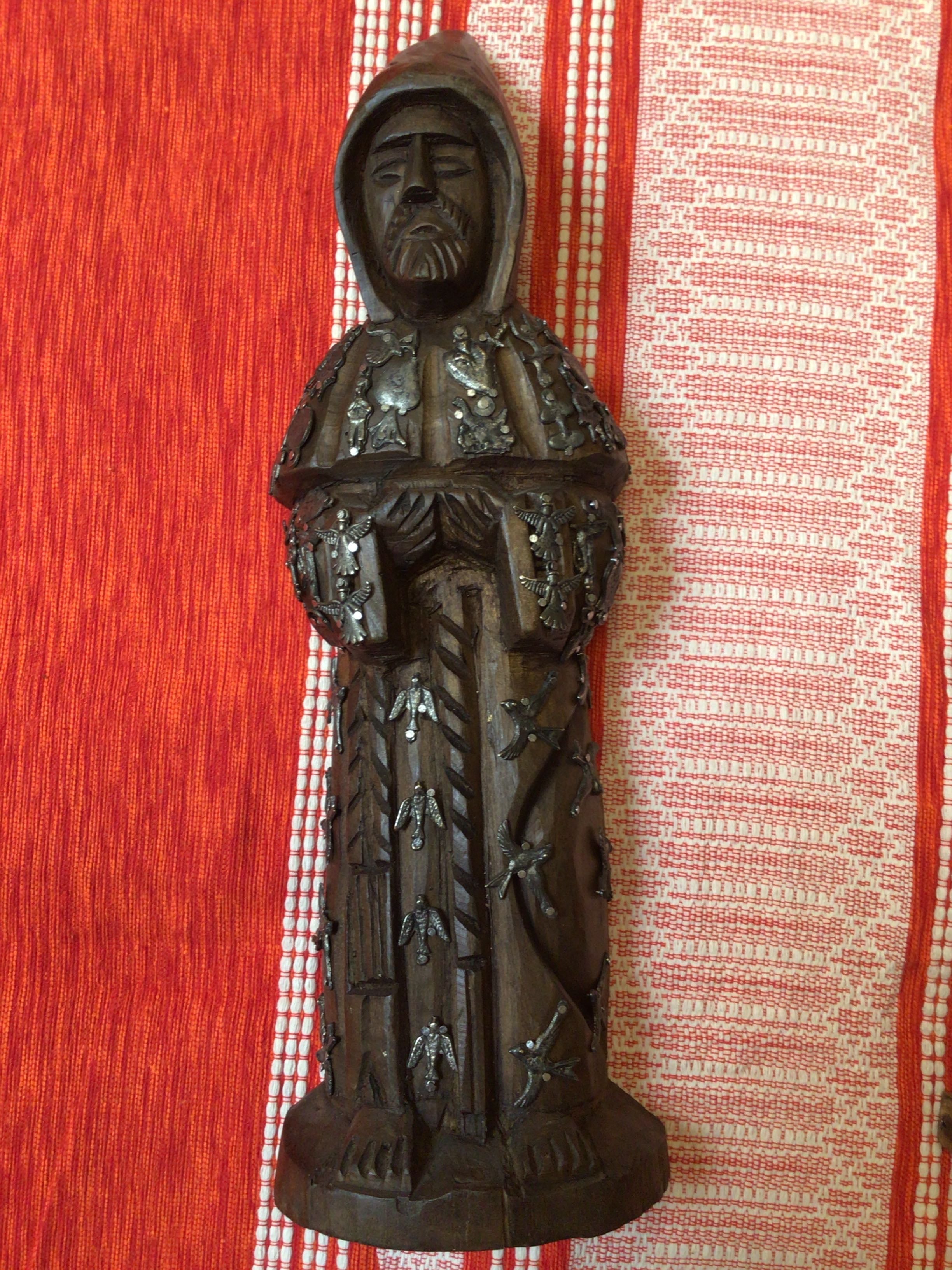 Bronze statue of a hooded figure on a red and white checkered background
