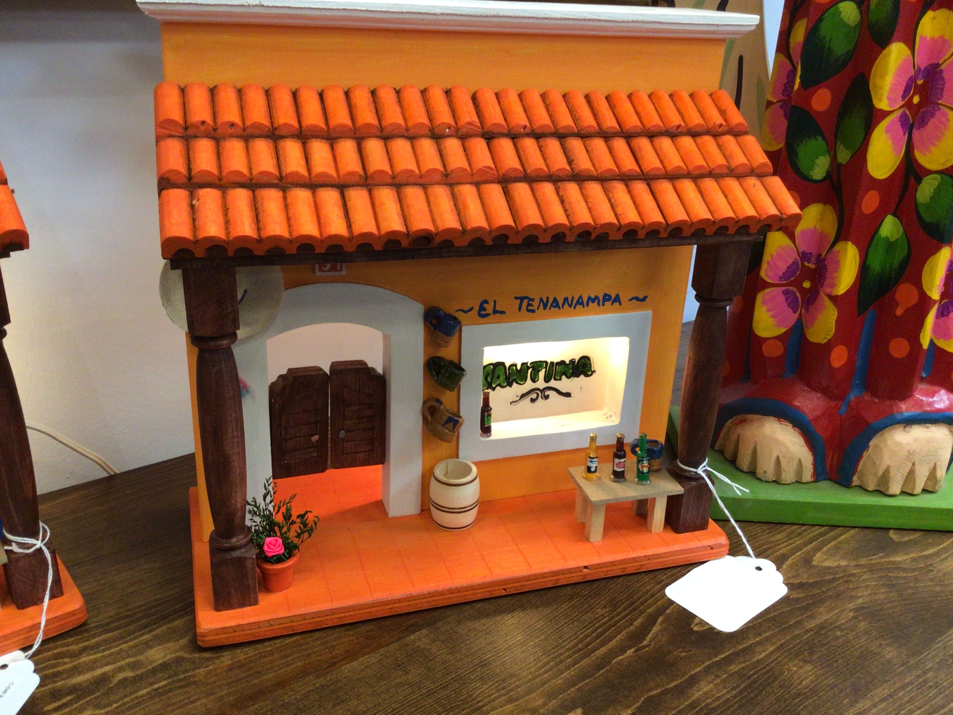Miniature model of a building with an orange roof and decorative elements on a wooden surface.