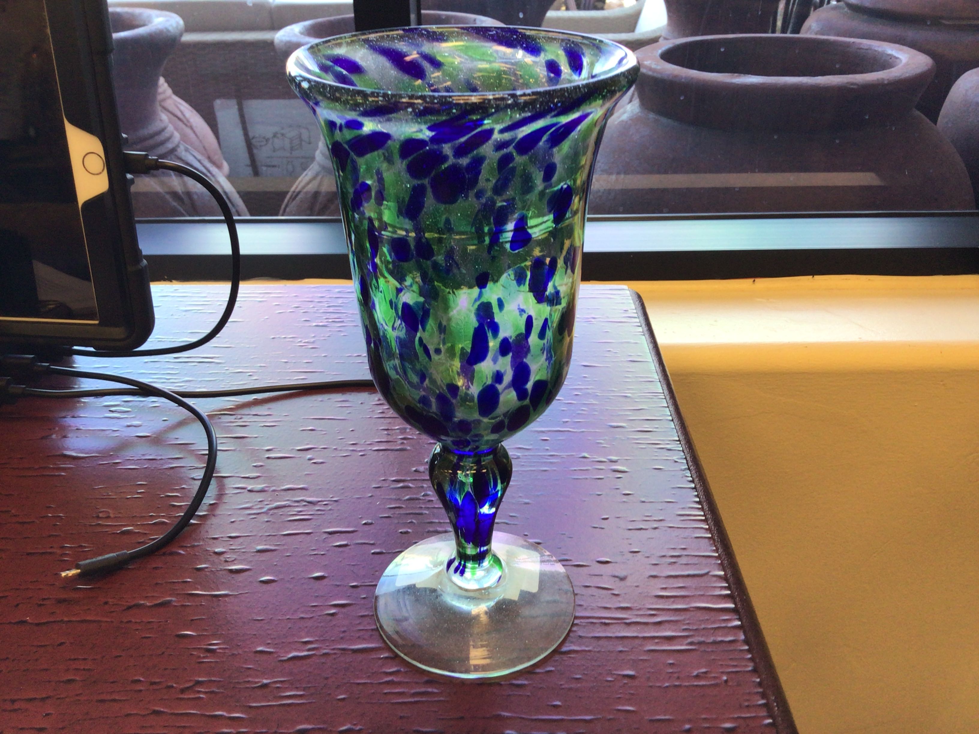 Decorative glass with blue and green pattern on a wooden surface