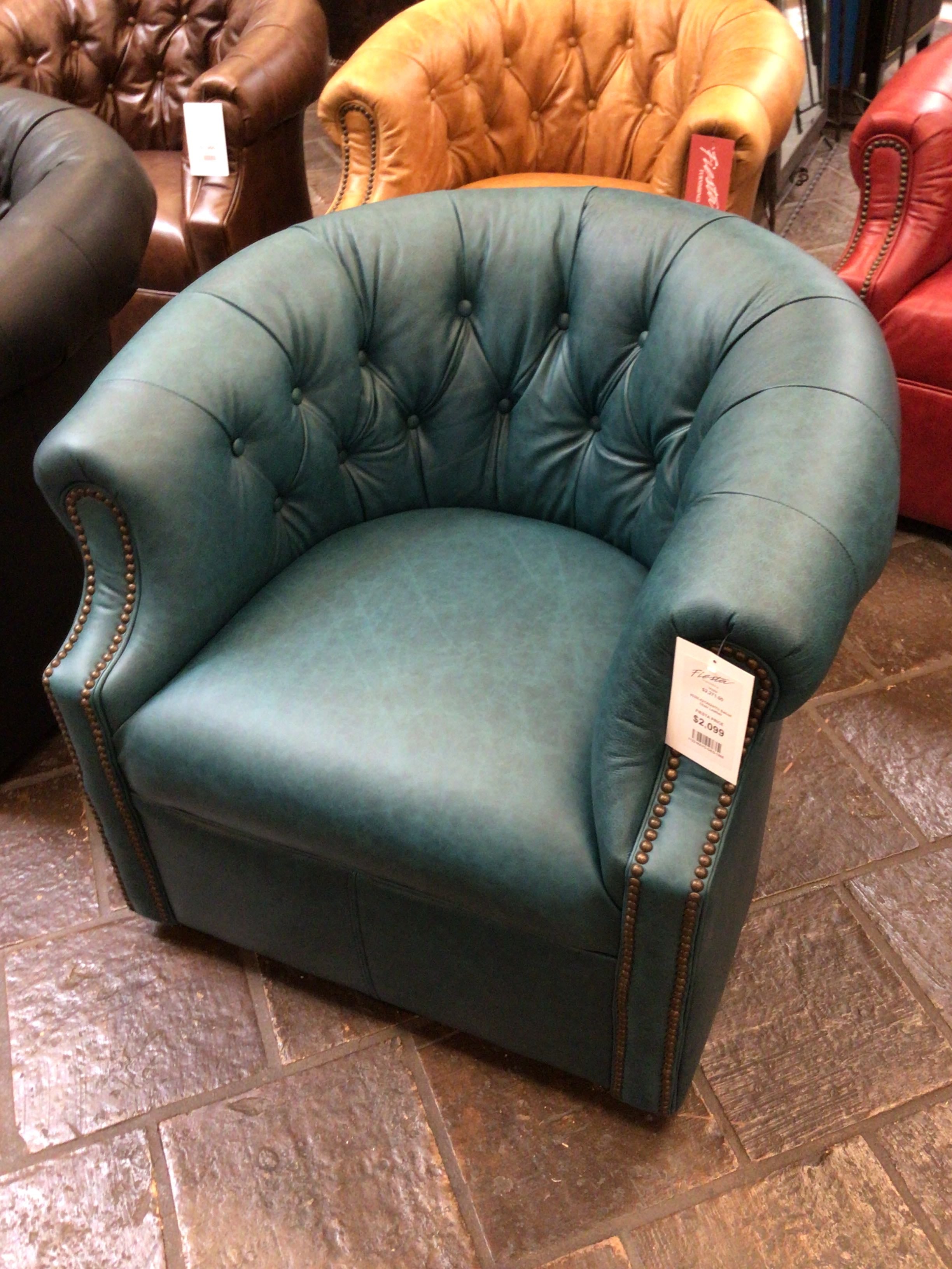 Green leather armchair with tufted backrest in a showroom setting
