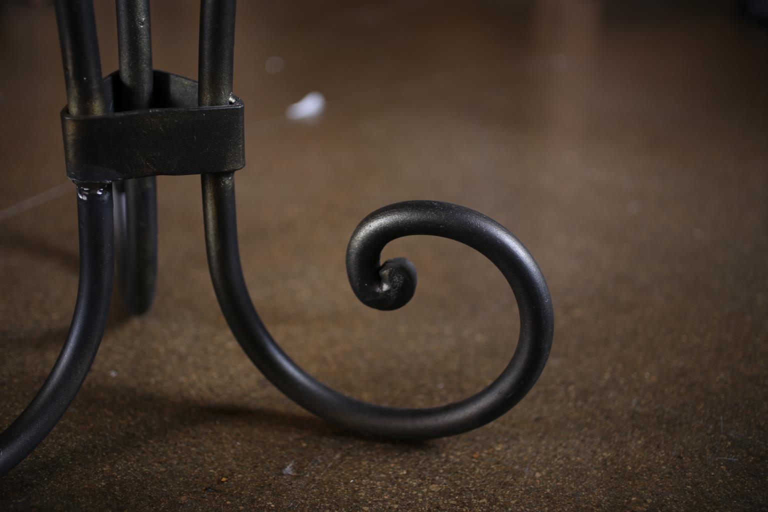 Close-up of a black metal candle holder with a decorative spiral design on a brown background.