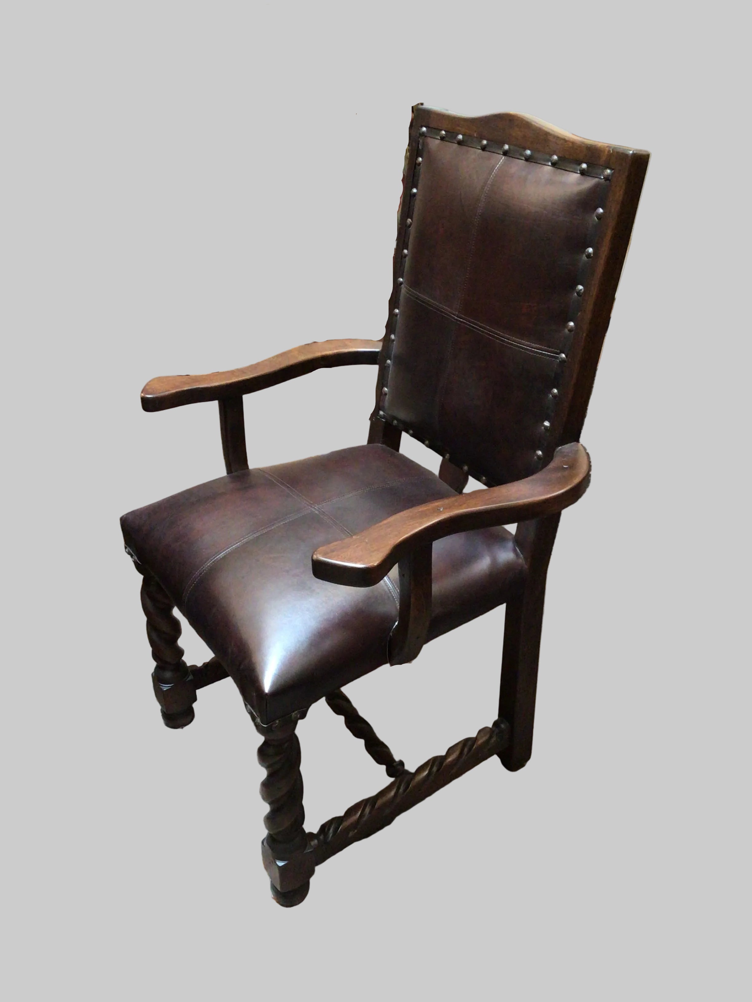 Brown leather armchair with wooden armrests on a gray background