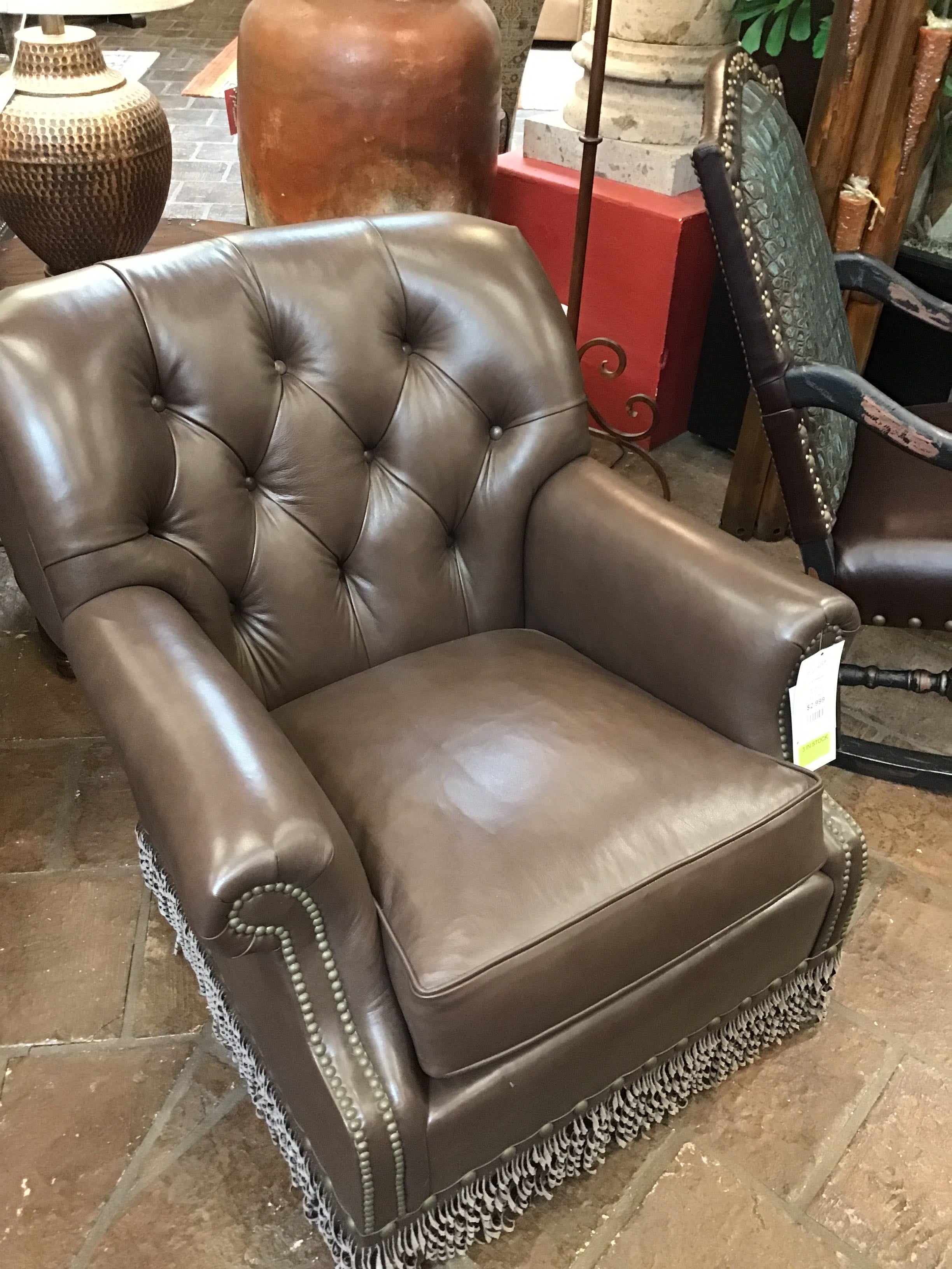 Brown leather armchair with tufted backrest in a room setting