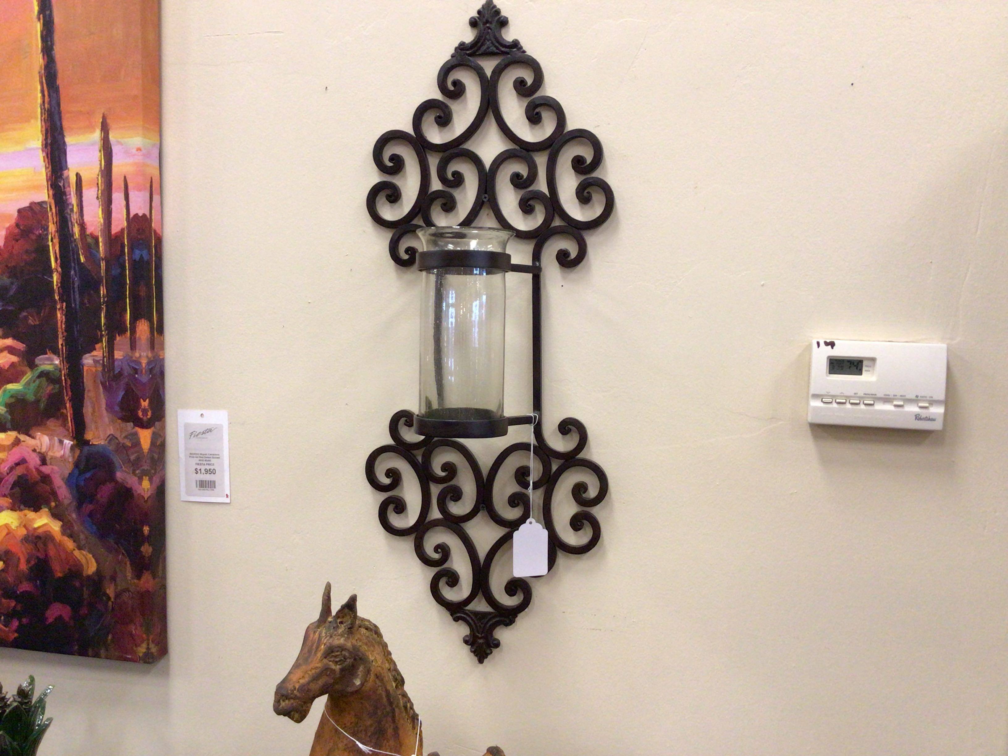 Decorative wall sconce with a candle holder on a beige wall next to a colorful painting and a horse statue.