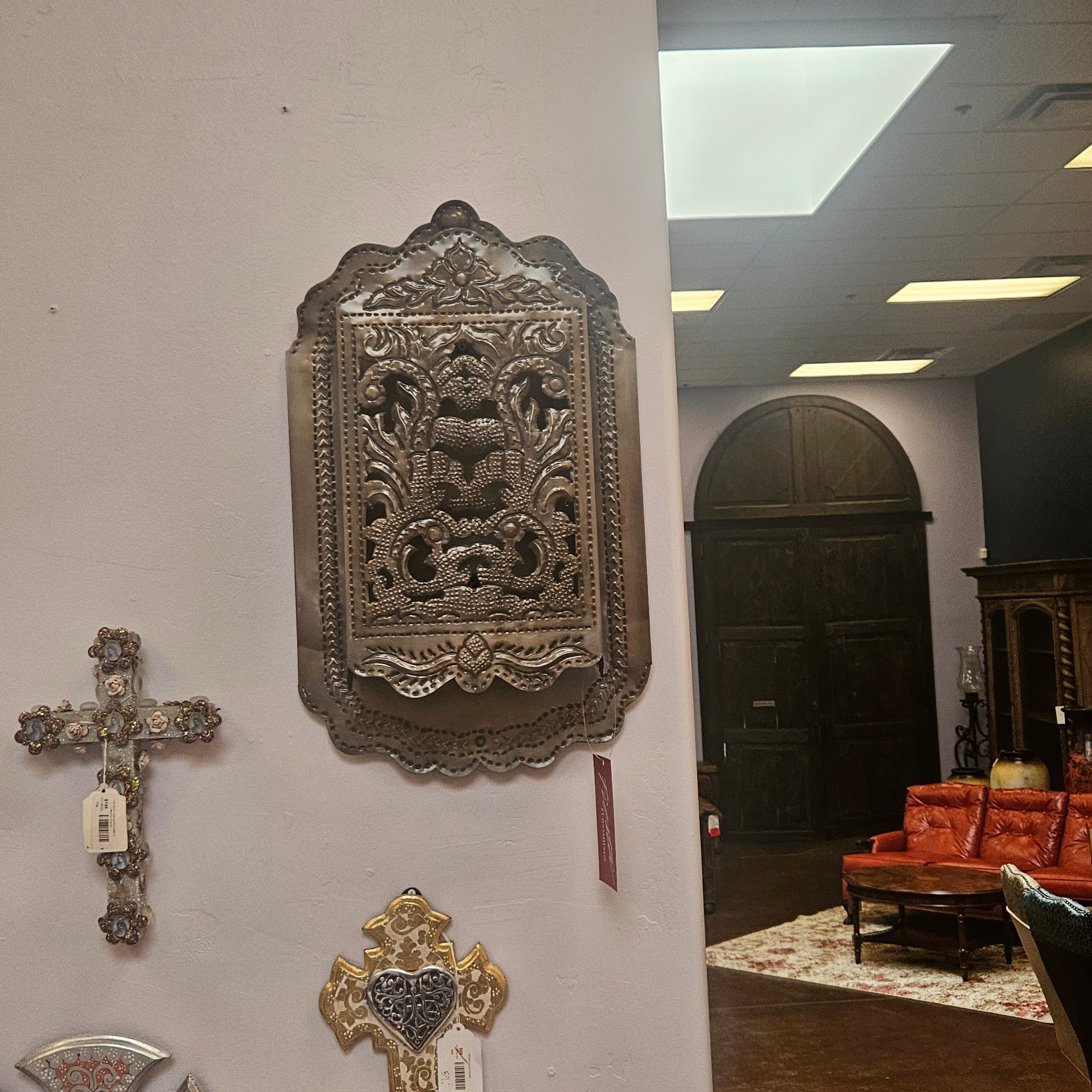 Decorative wall art pieces on a white wall with a red couch and wooden door in the background.