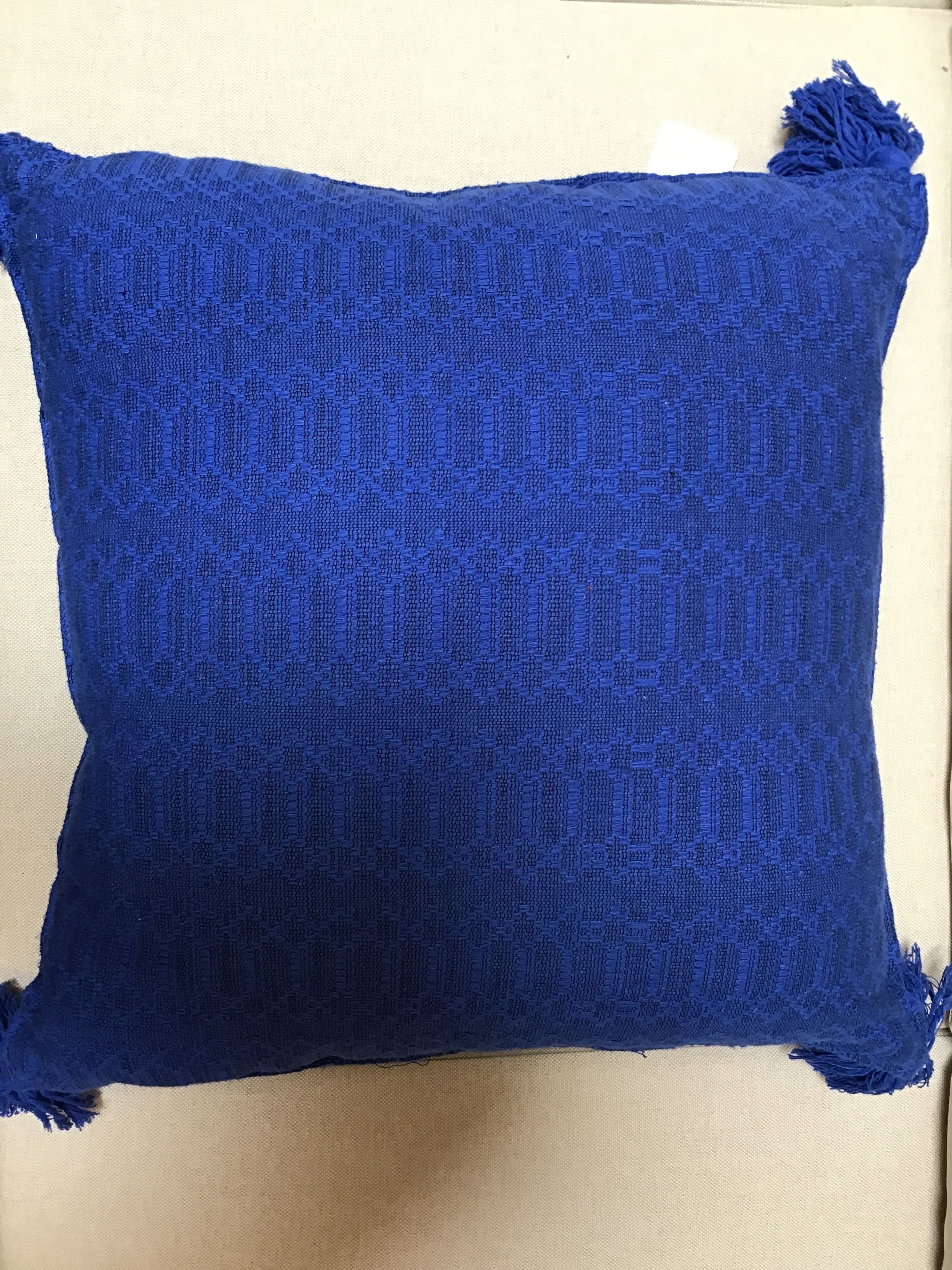 Blue textured pillow with tassels on a beige background