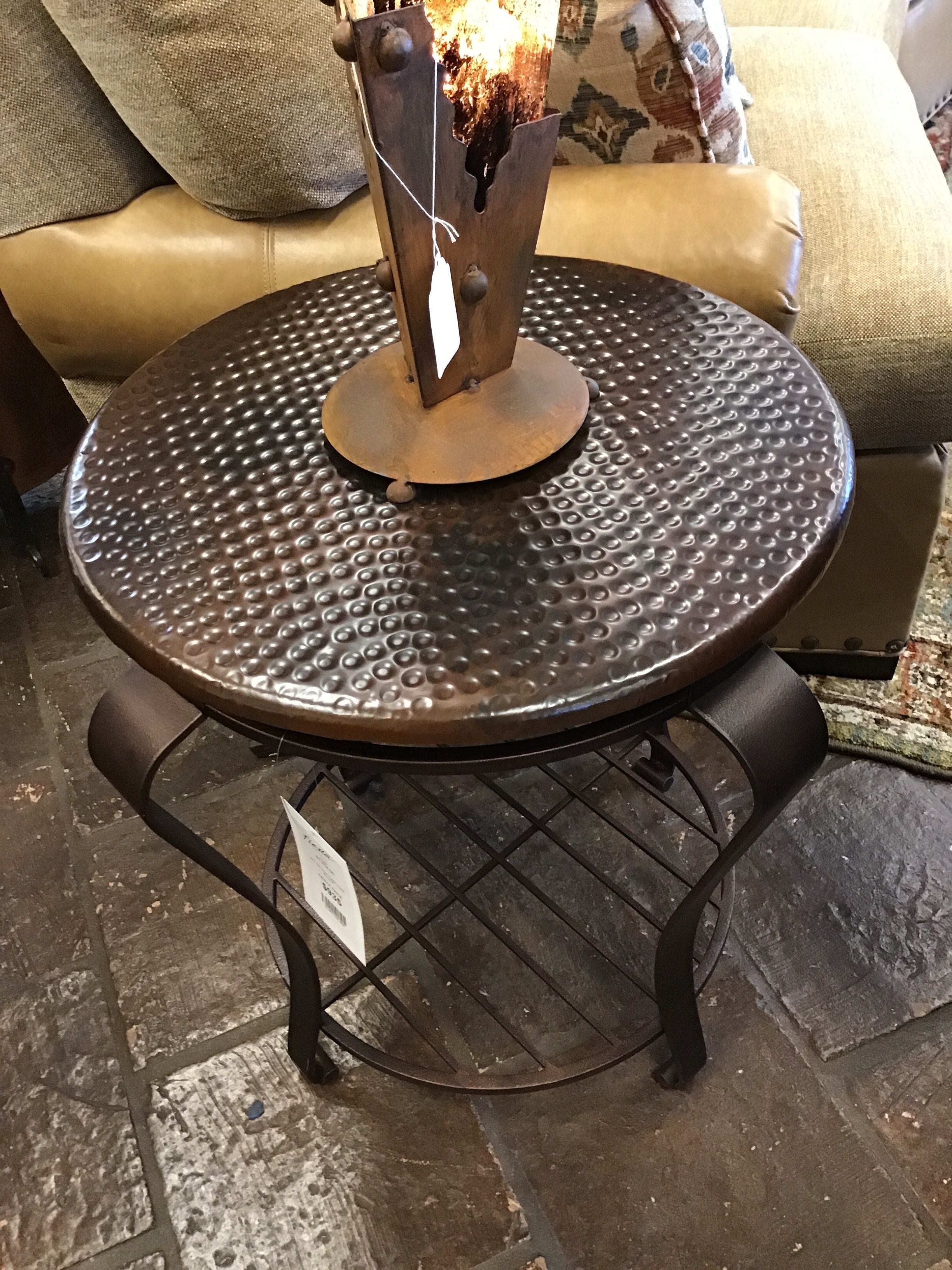 Round metal table with textured surface on a stone floor