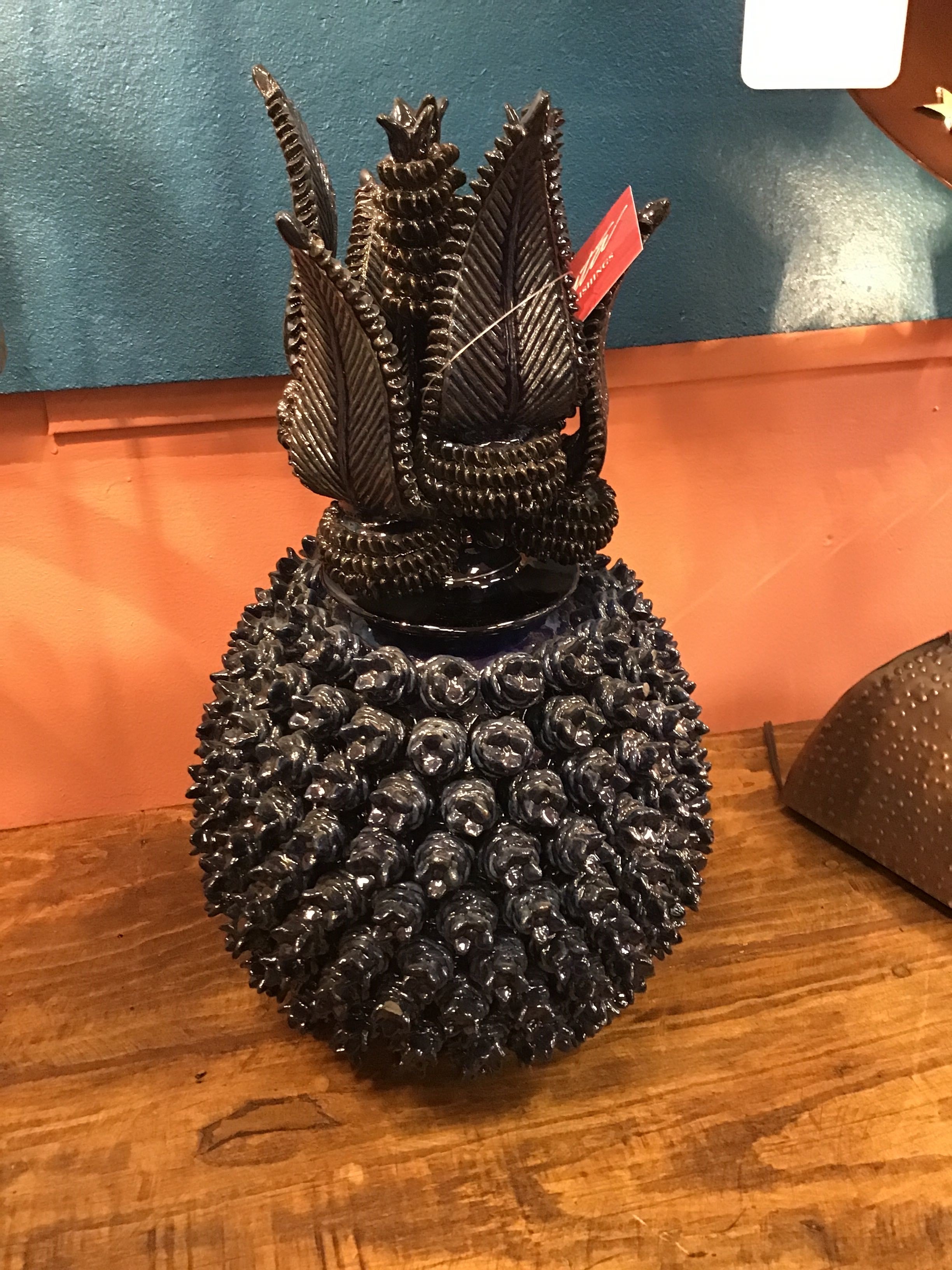 Decorative black pineapple with a red tag on a wooden surface