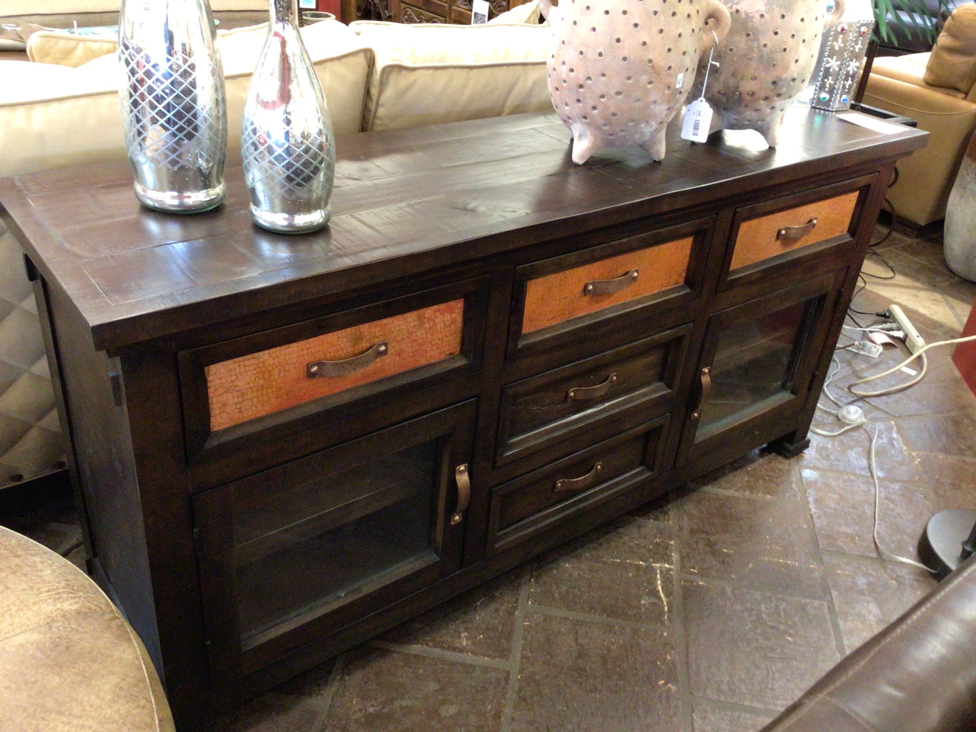 Dark wooden sideboard with multiple drawers and glass doors in a living room setting.
