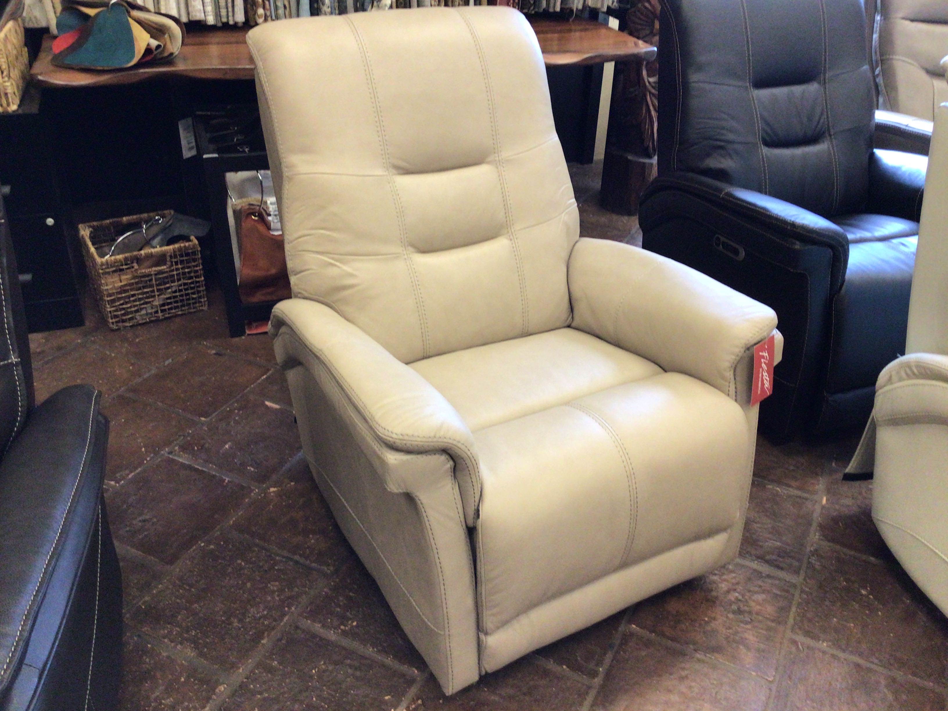 Beige recliner chair in a showroom setting with other furniture.