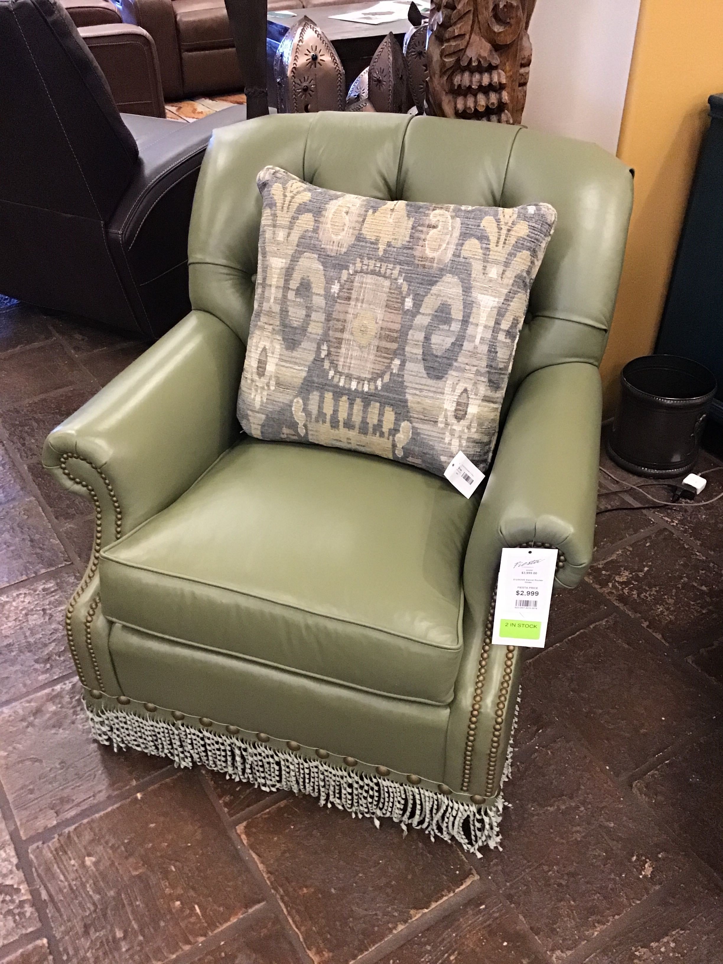 Green leather armchair with a patterned pillow on a tiled floor