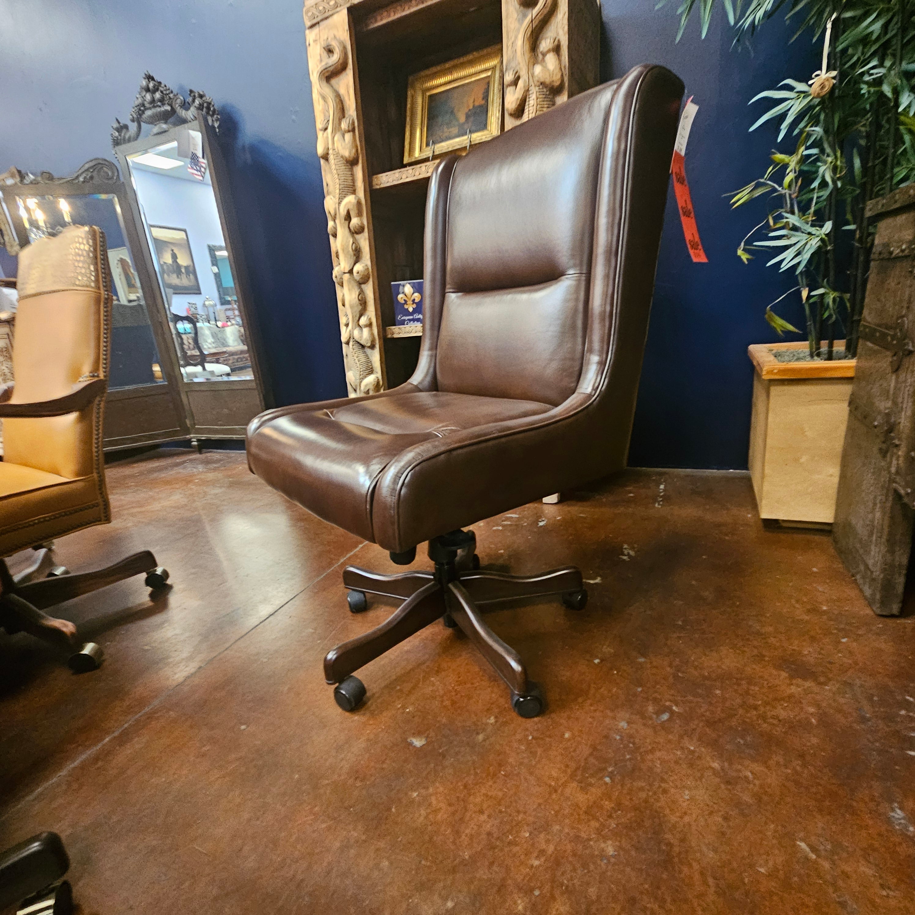 Brown office chair on a wooden floor with a decorative wall and mirror in the background.