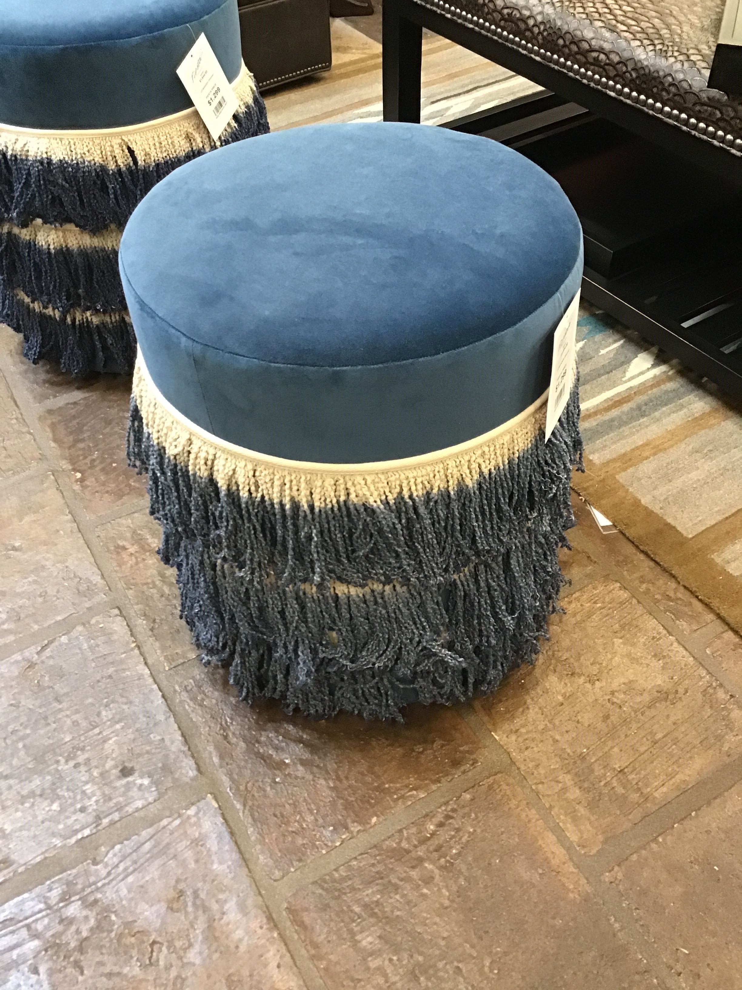 Blue ottoman with fringe on a stone floor