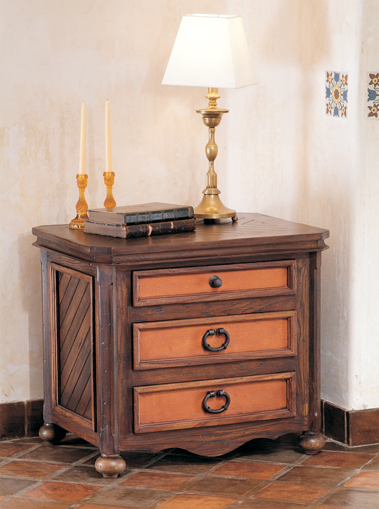 Wooden nightstand with drawers, lamp, and candles on a tiled floor.