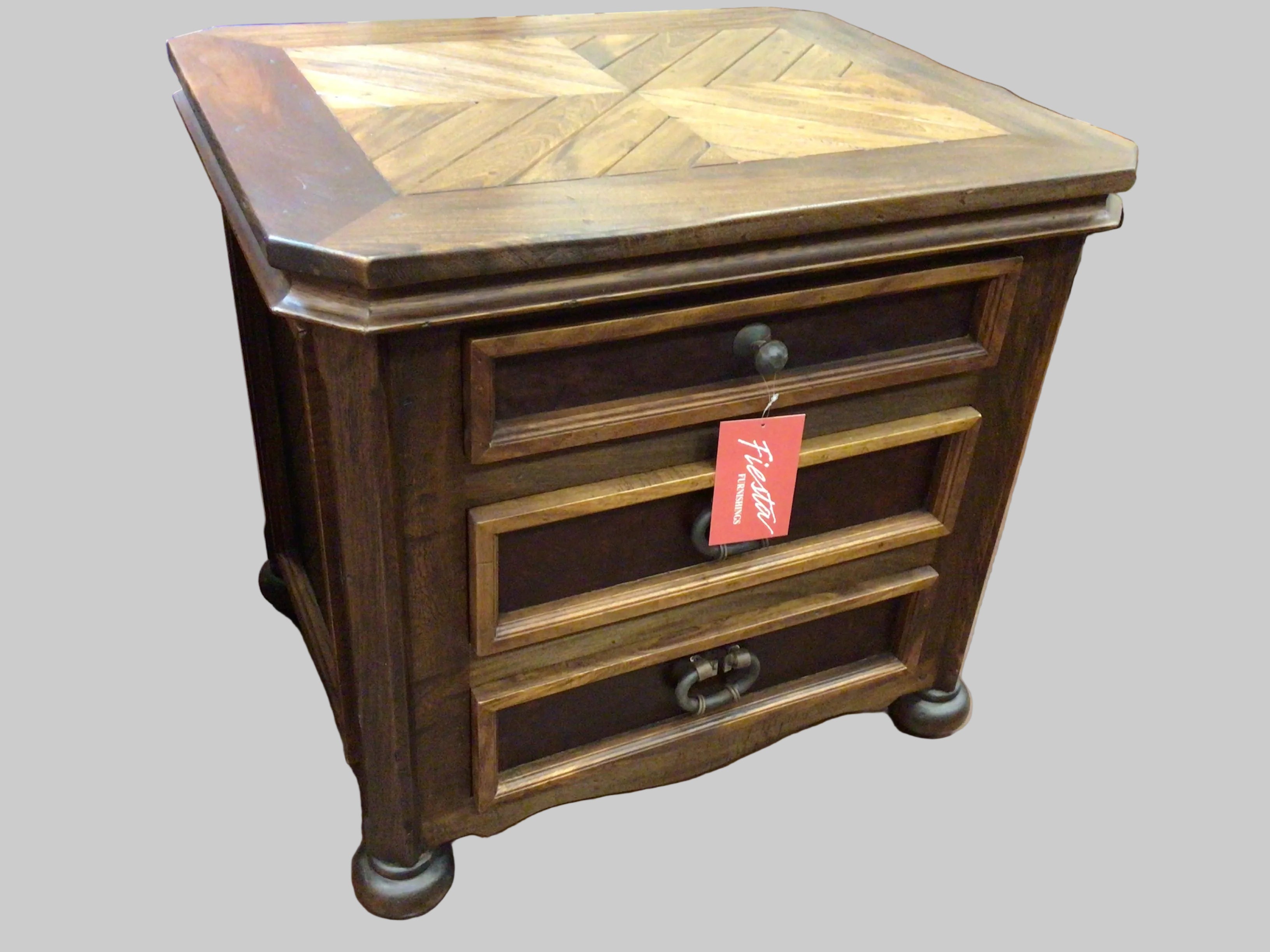 Wooden nightstand with three drawers on a brown floor, featuring a price tag.