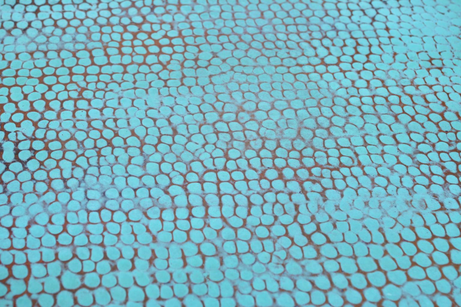 Close-up of a hammered turquoise copper surface.
