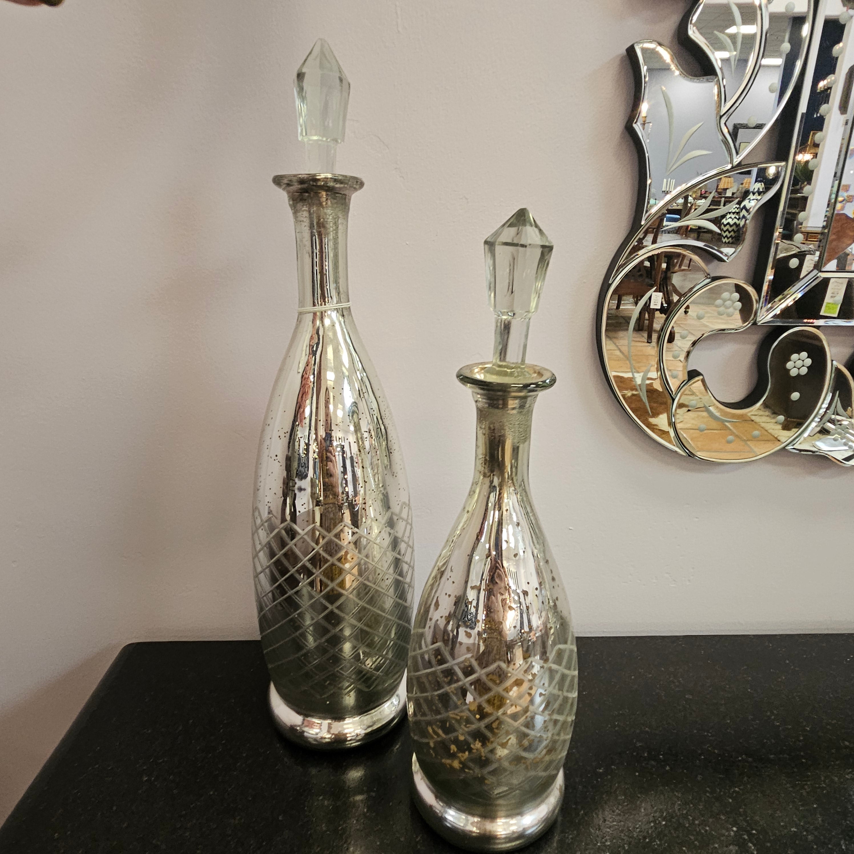 Two silver decorative bottles with crystal tops on a light background