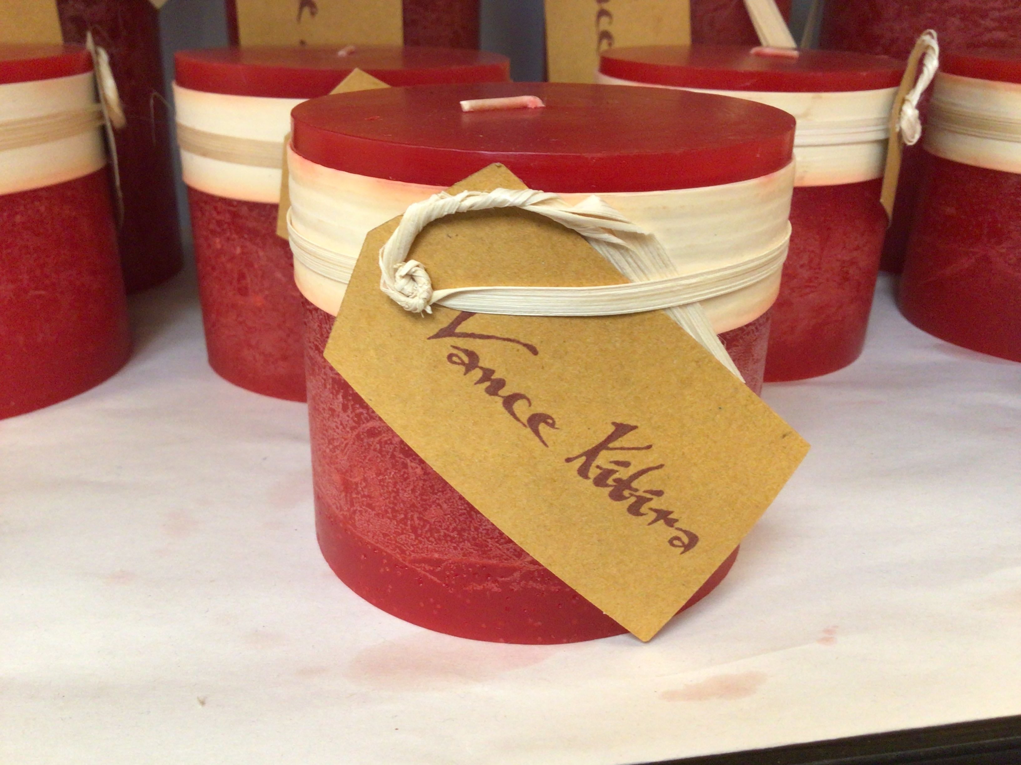Red candles with beige ribbons and tags on a white surface