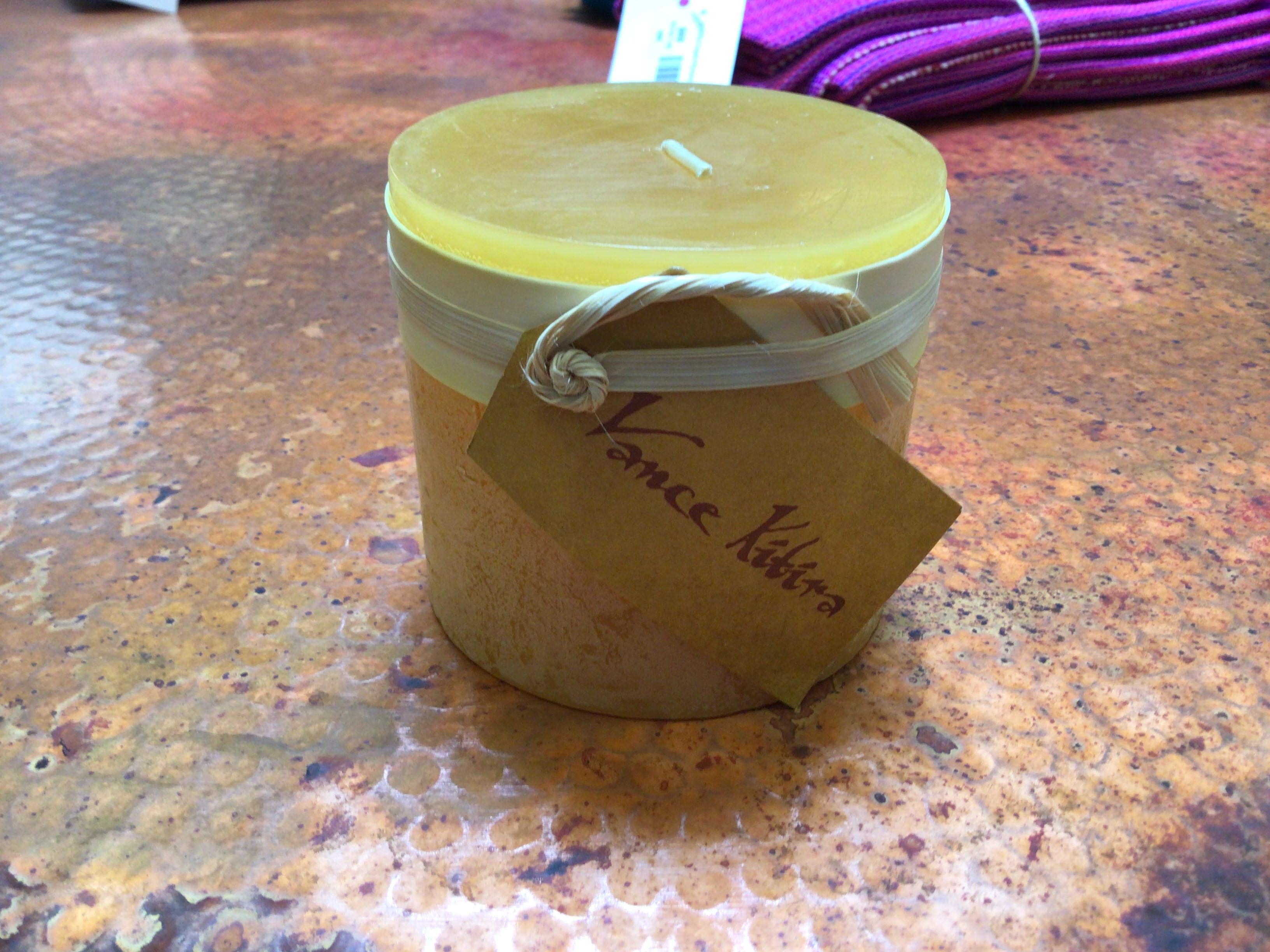 Small jar candle with a visible brand name on a textured surface