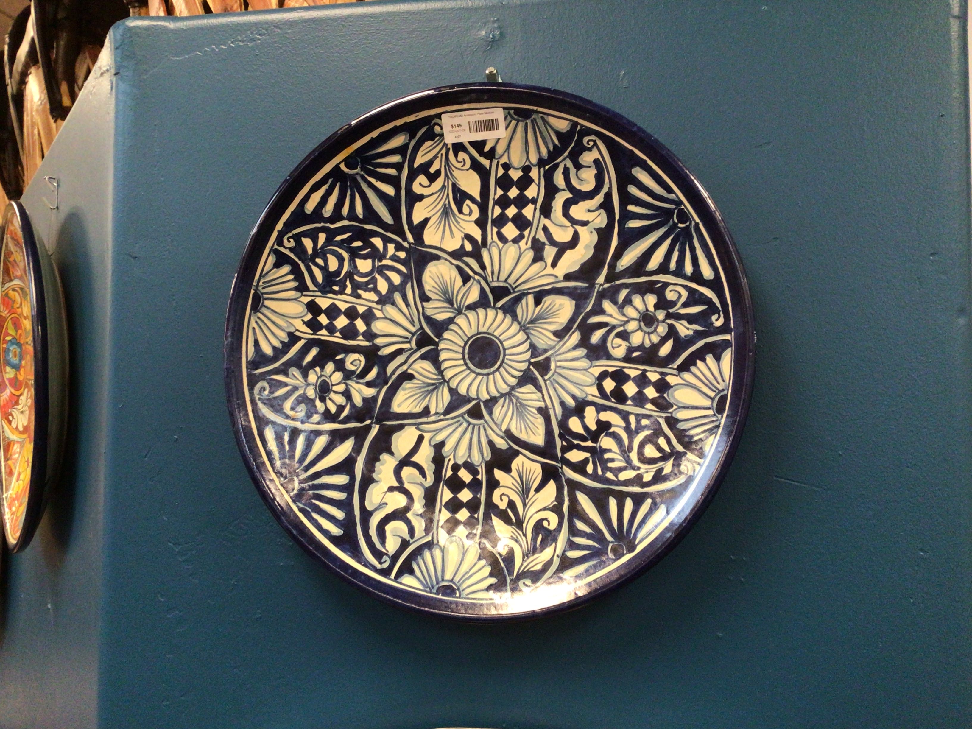 Decorative ceramic plate with intricate patterns on a teal wall.