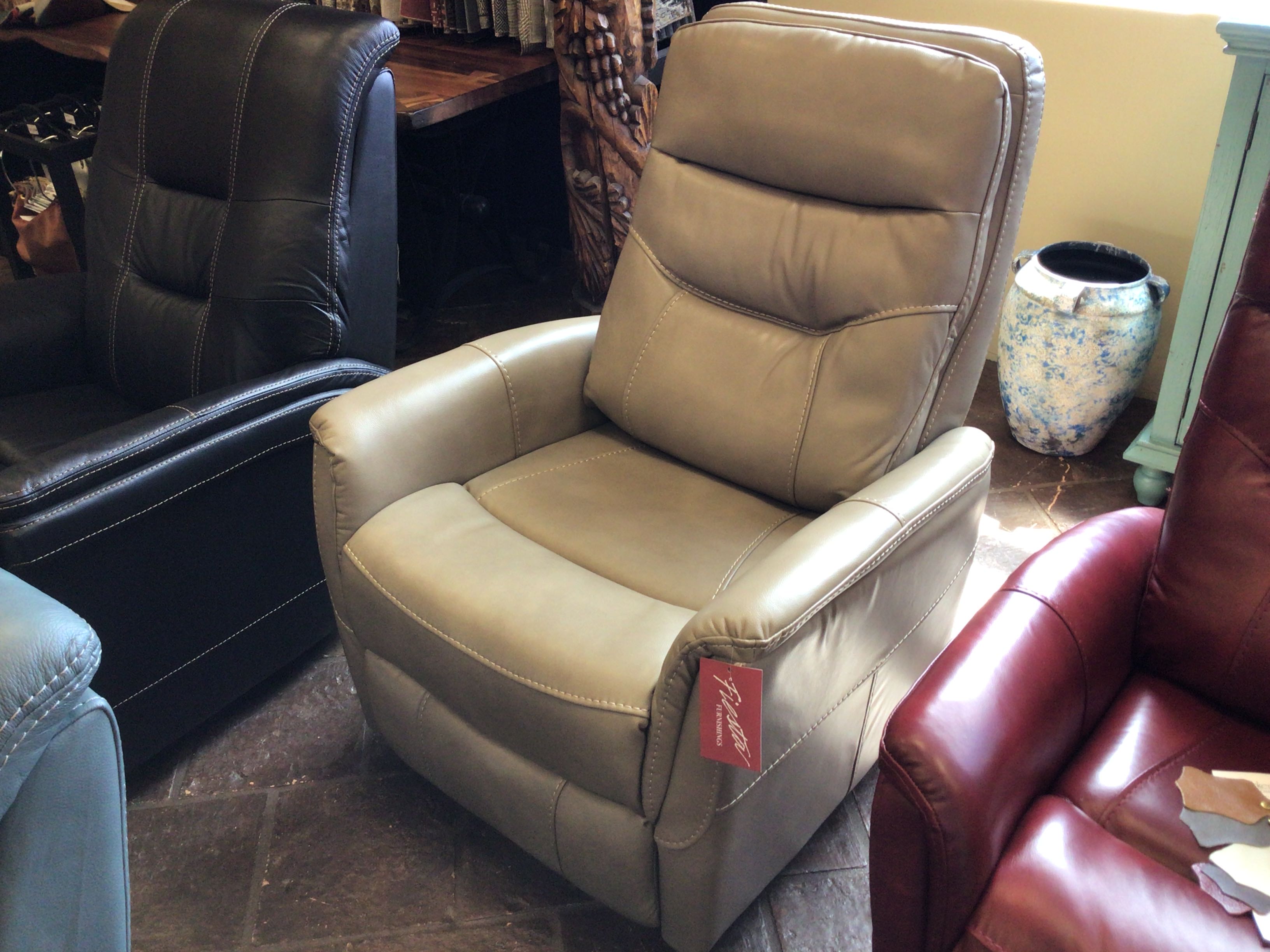 Beige leather recliner chair with a visible brand tag in a showroom setting.