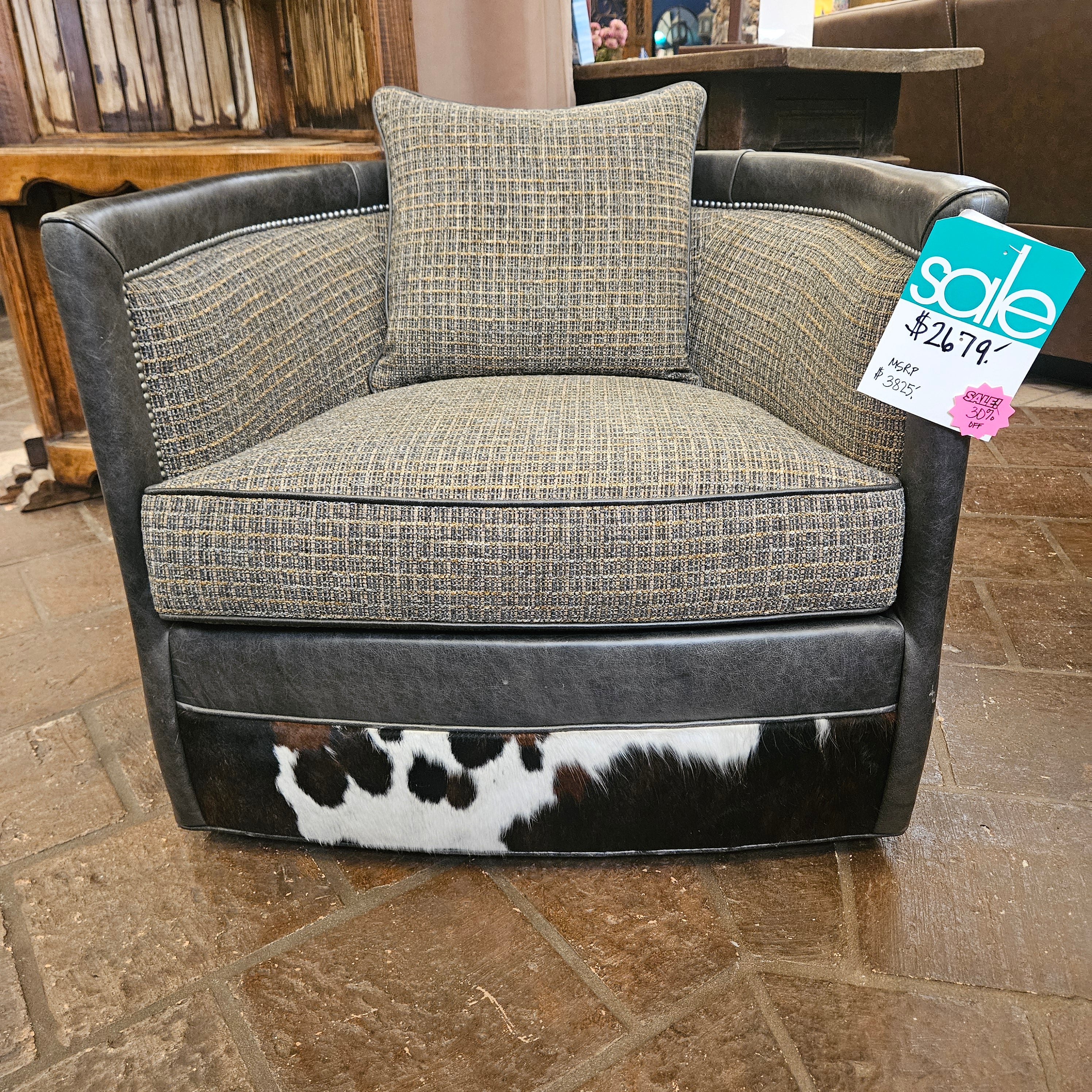 Sofa with patterned cushions on a tiled floor, with sale tags attached.