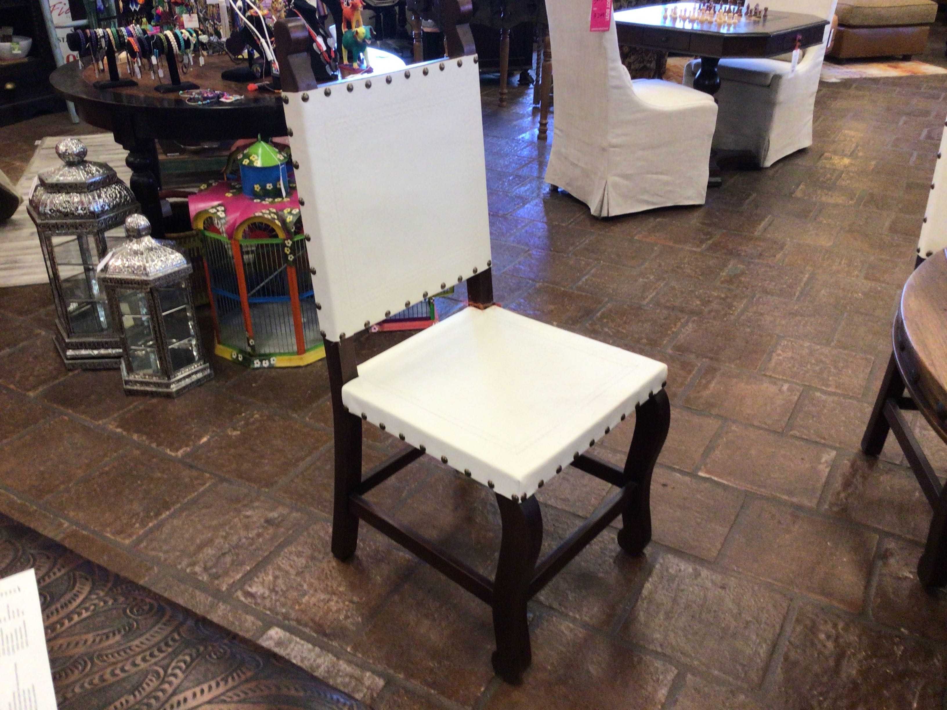 White chair with black legs on a stone floor in an indoor setting