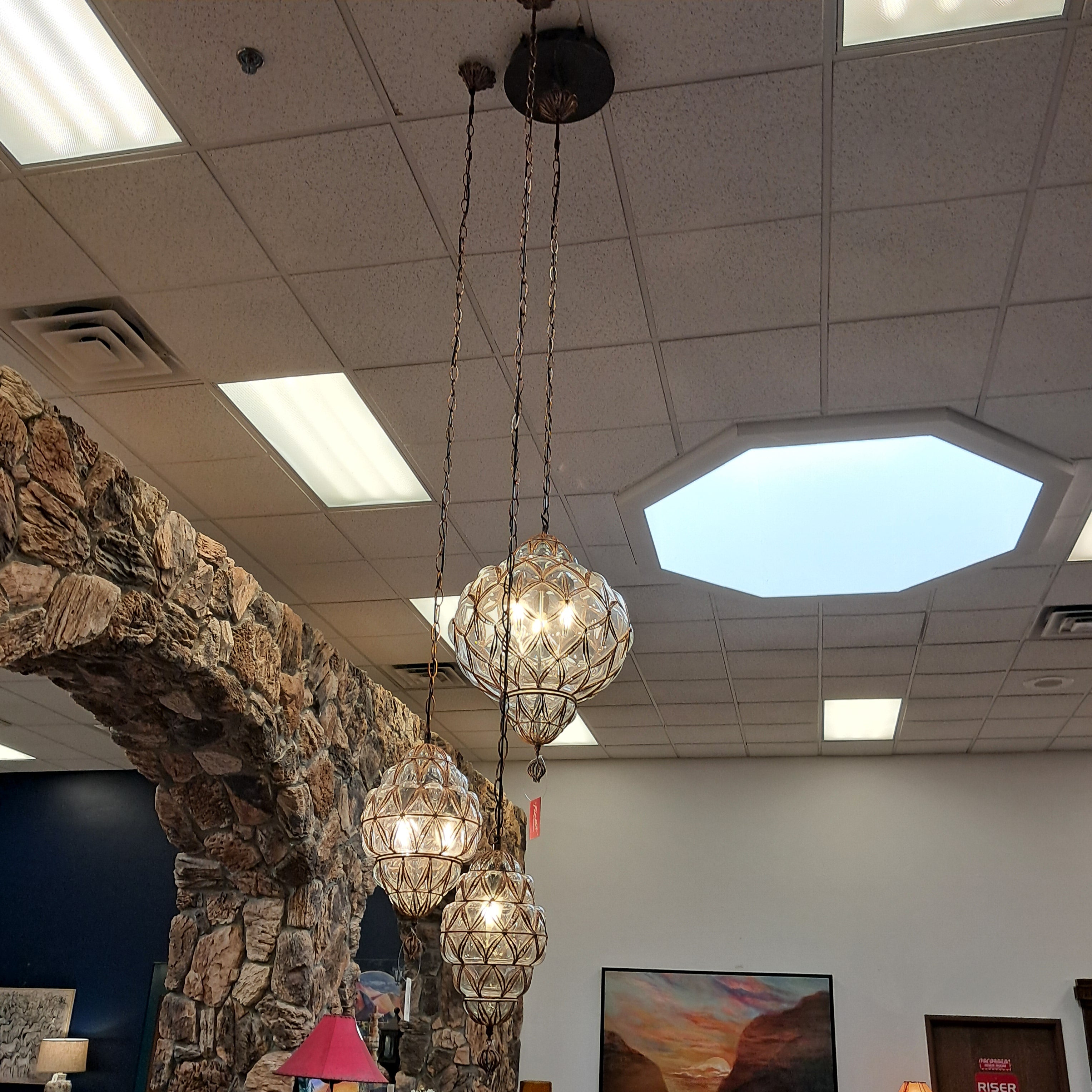Ceiling light fixture with stone wall and octagonal window in the background
