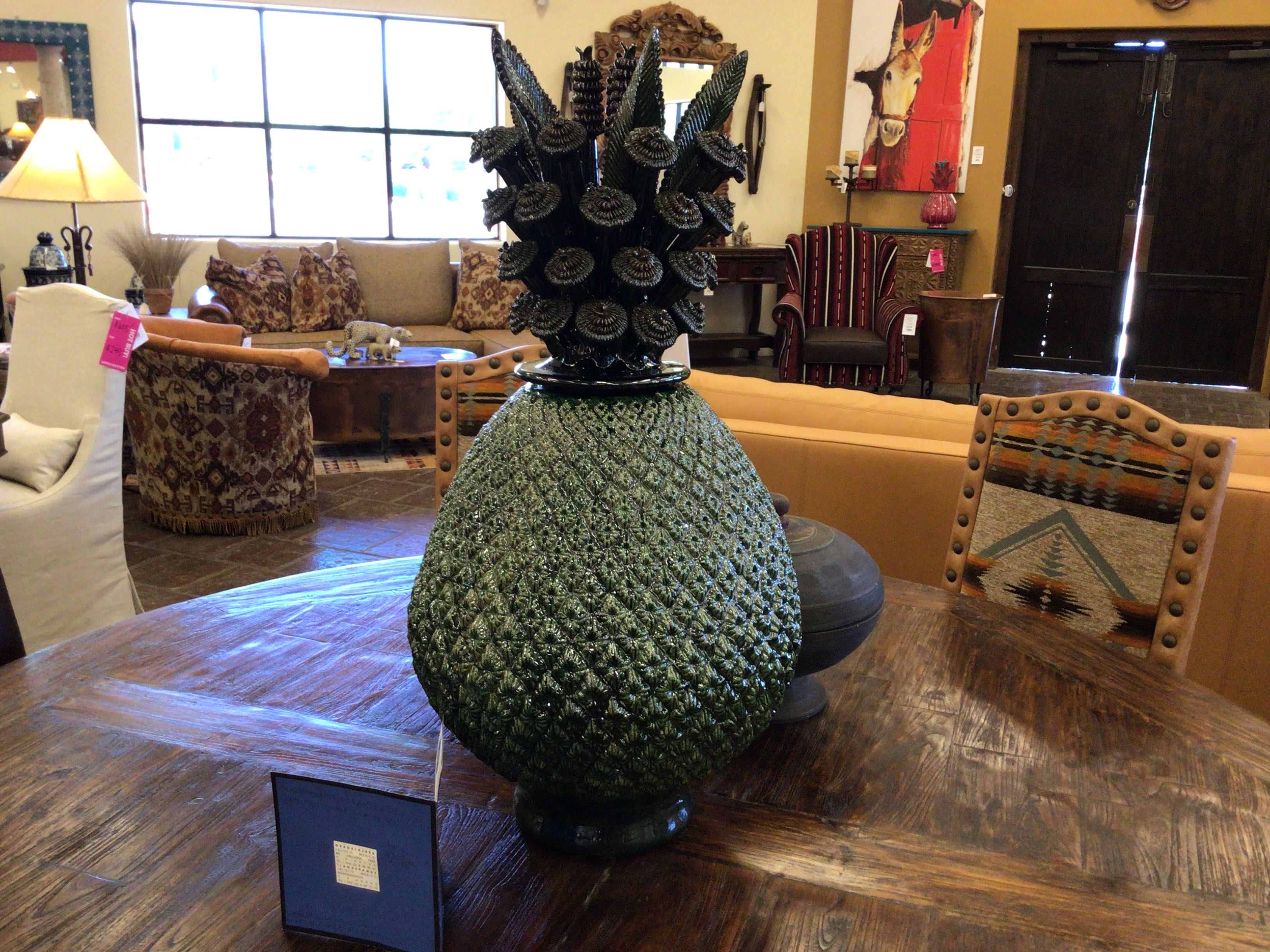 Decorative pineapple-shaped vase on a wooden table in a room with furniture and decor.