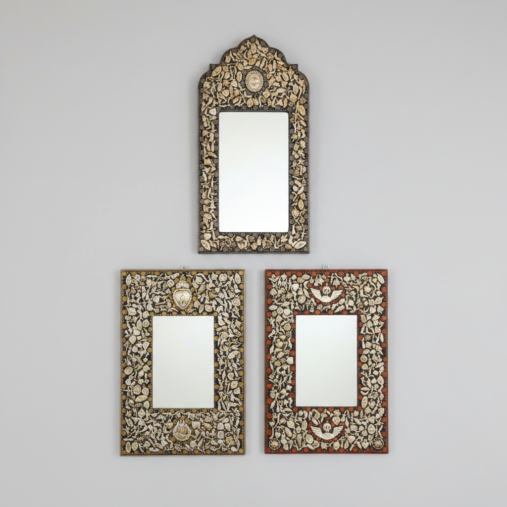 Three ornate decorative wall mirrors with intricate carved frames hang on a light gray wall. The top mirror has an arched top and dark frame, while the two mirrors below have rectangular frames, one in reddish-brown and one in dark brown, all featuring detailed floral inlay around the mirror glazing.