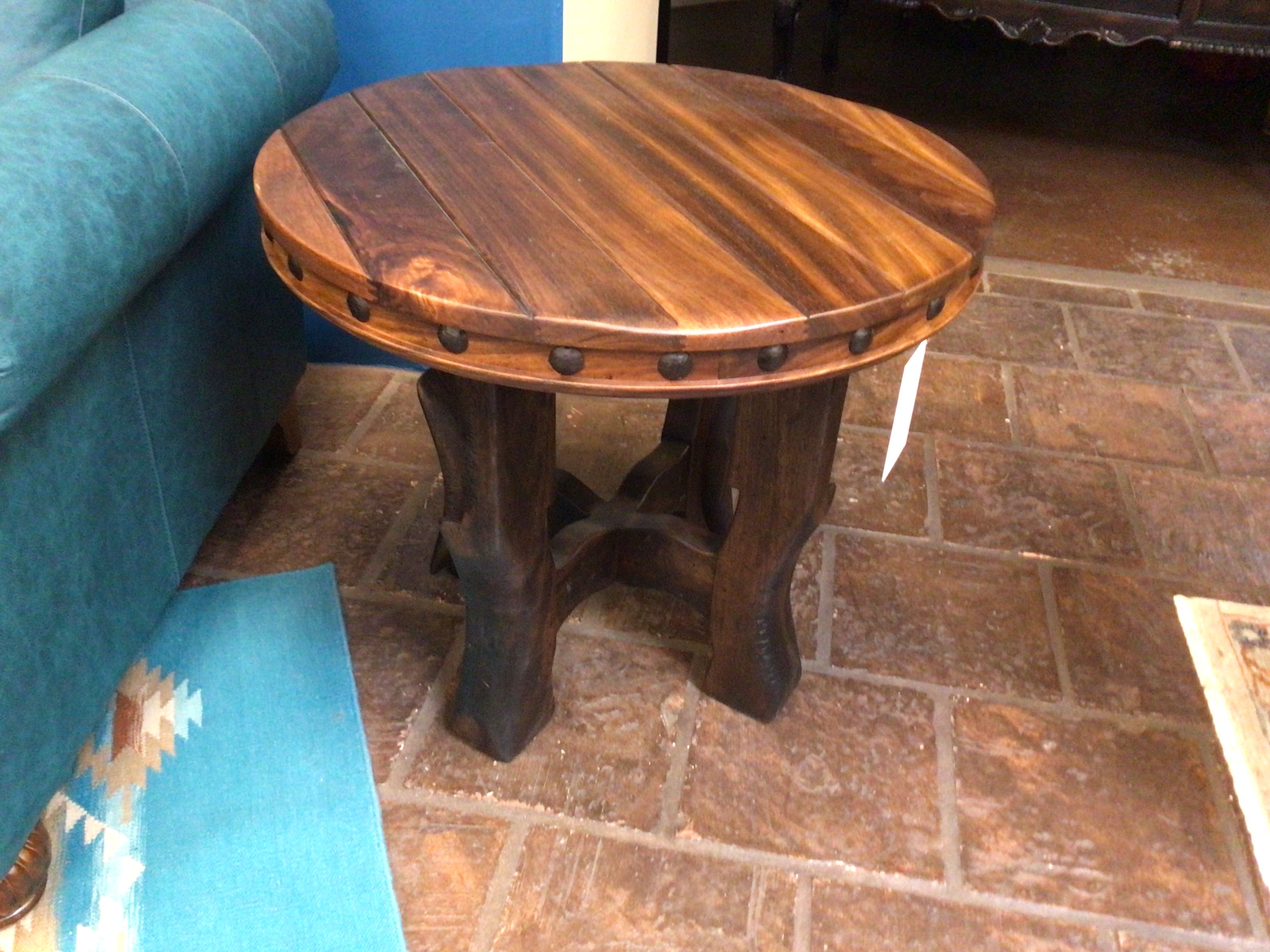 Wooden side table on a stone floor with teal sofa in the background
