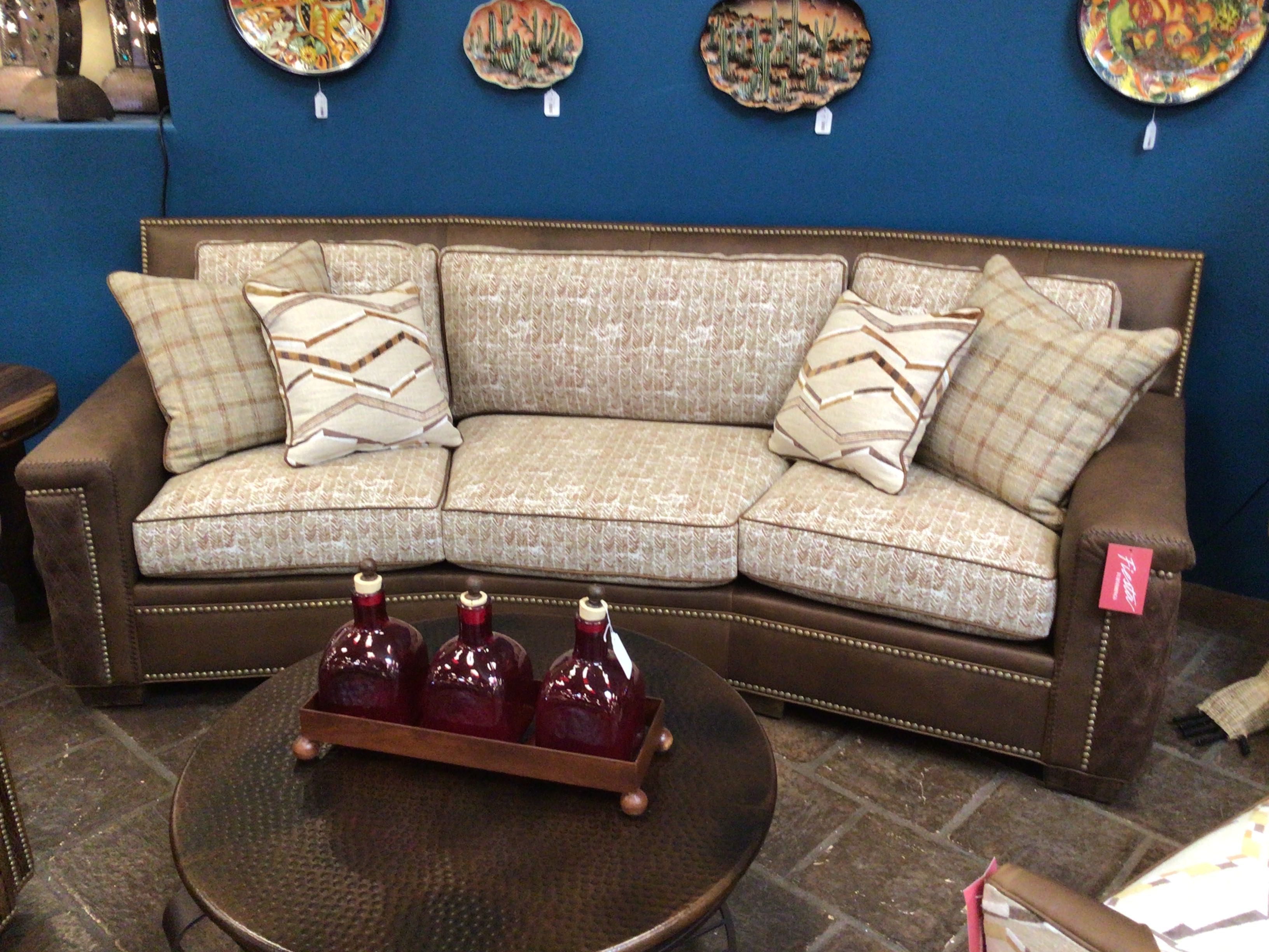 Brown sofa with patterned cushions in a room with decorative plates on the wall.