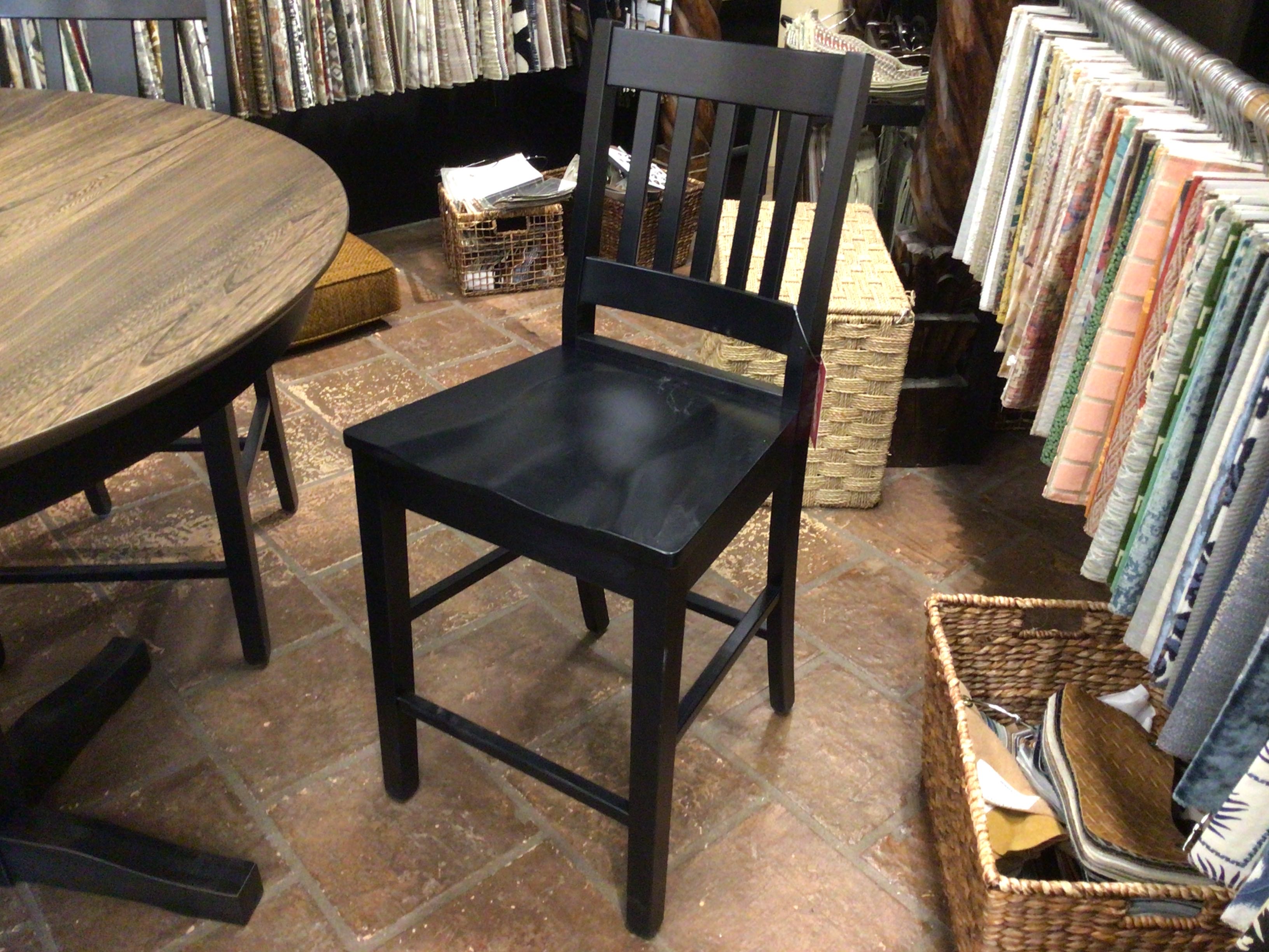 Black chair in a room with a wooden table and fabric samples.