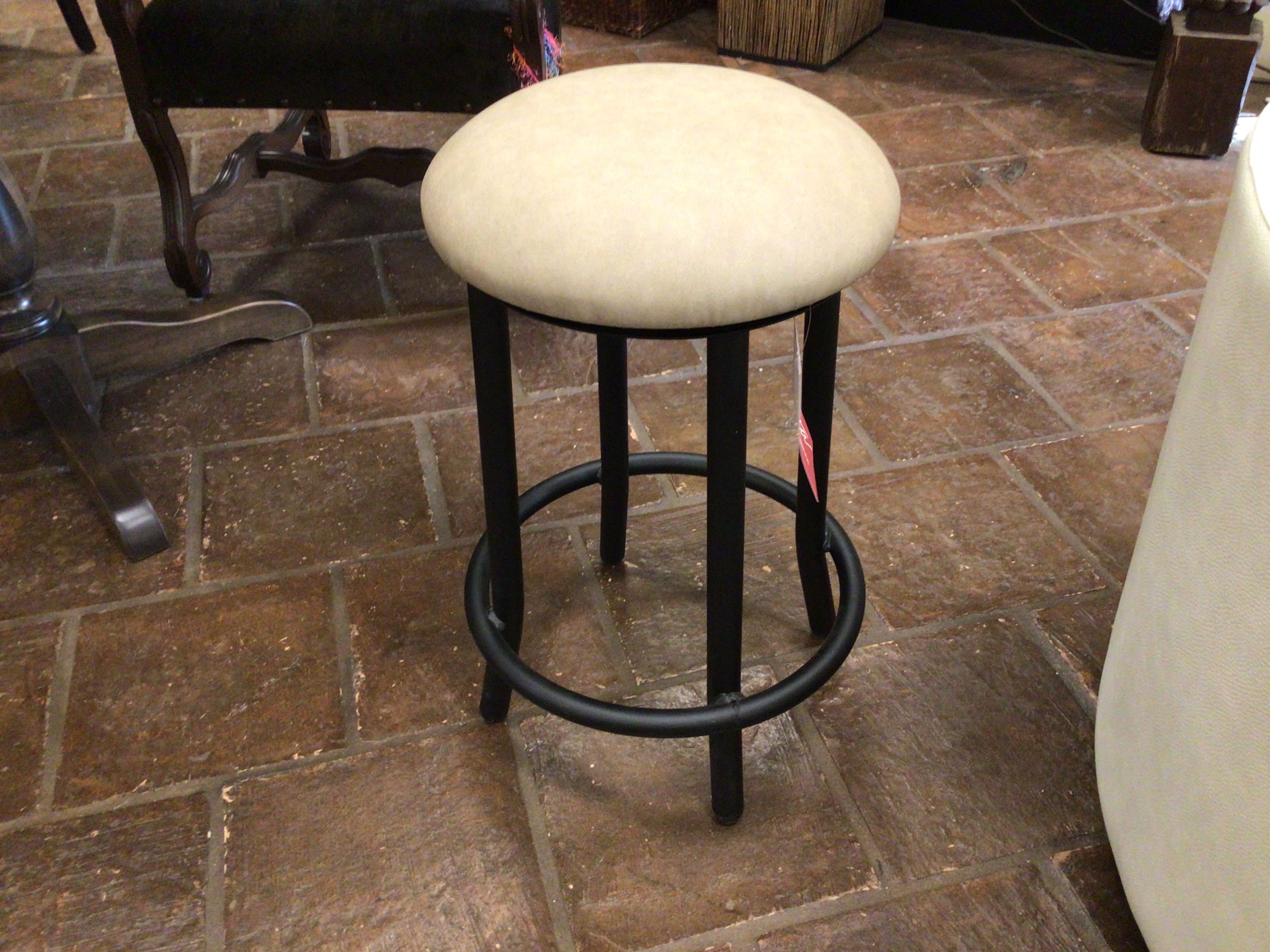 Bar stool with a white cushioned seat on a brick floor