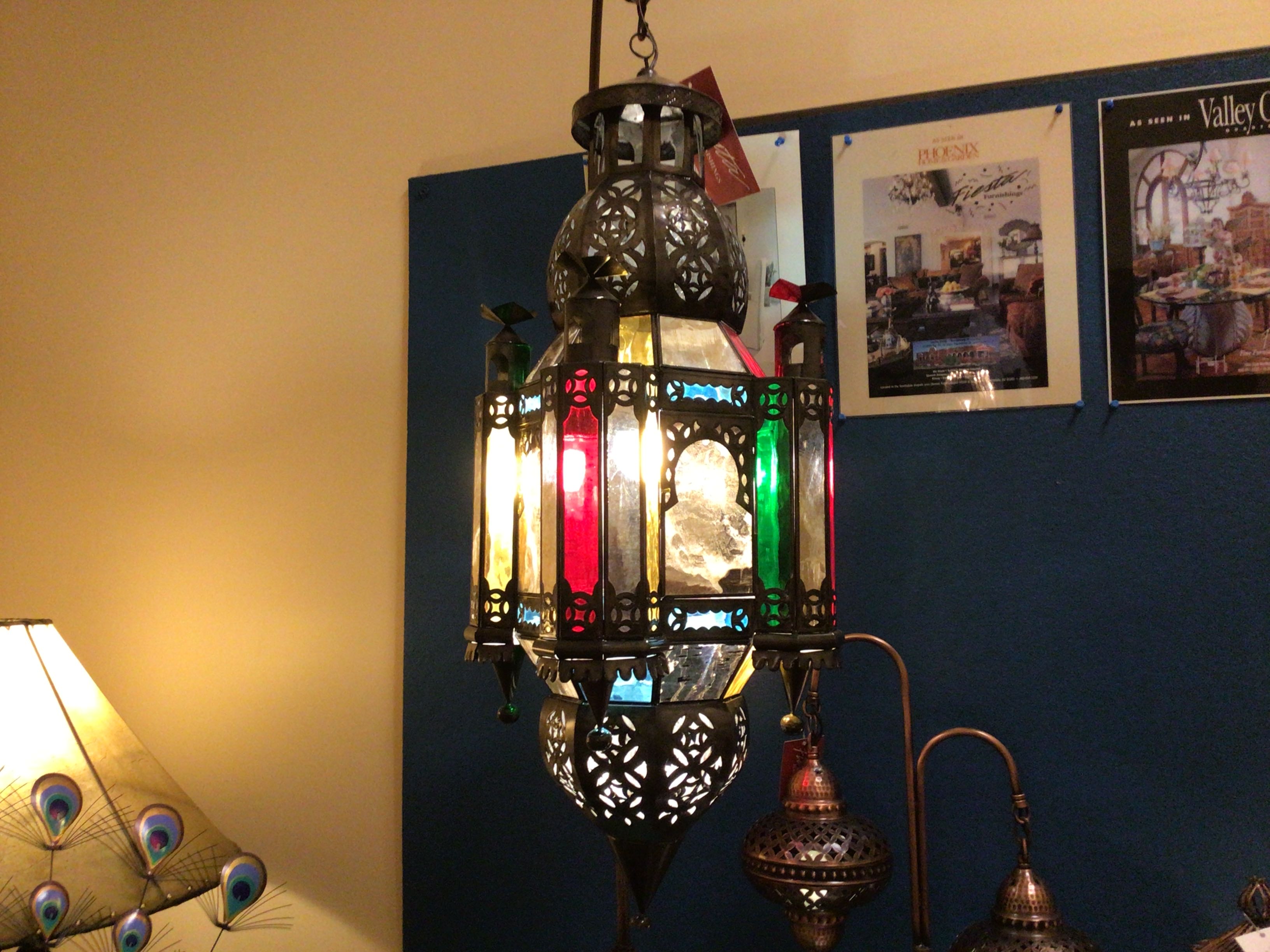Decorative hanging lantern with colorful glass panels in a room with posters on the wall.