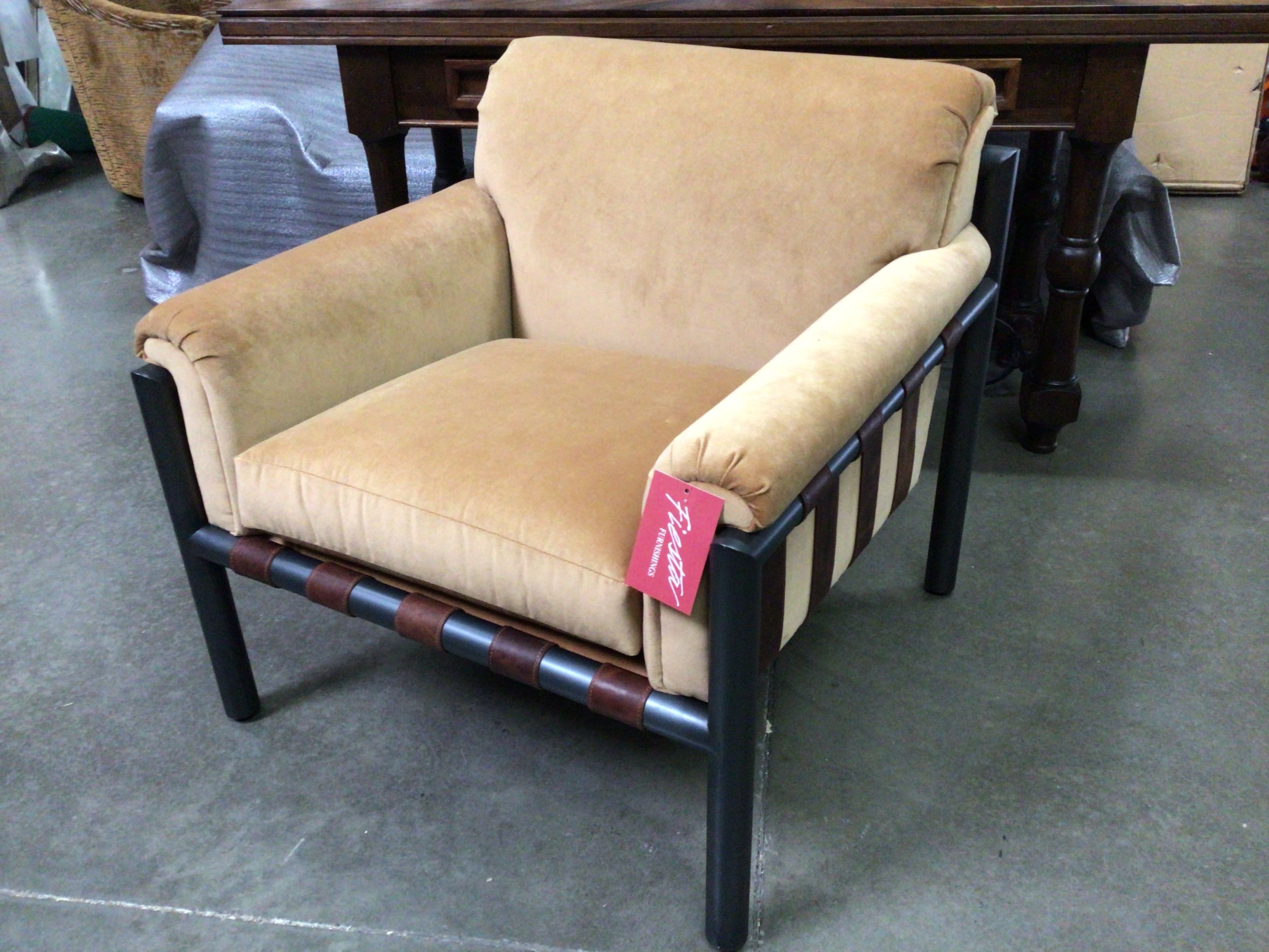 Beige armchair with black and brown frame on a concrete floor